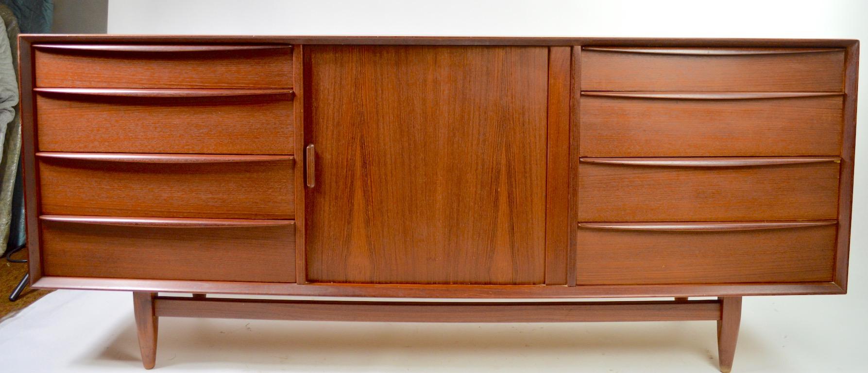 Nice Danish dresser in teak, by Falster. This example features two exposed banks of drawers flanking a center tambour roll section, which opens to reveal a set of interior drawers, providing ample storage space for garments etc. The cabinet is in