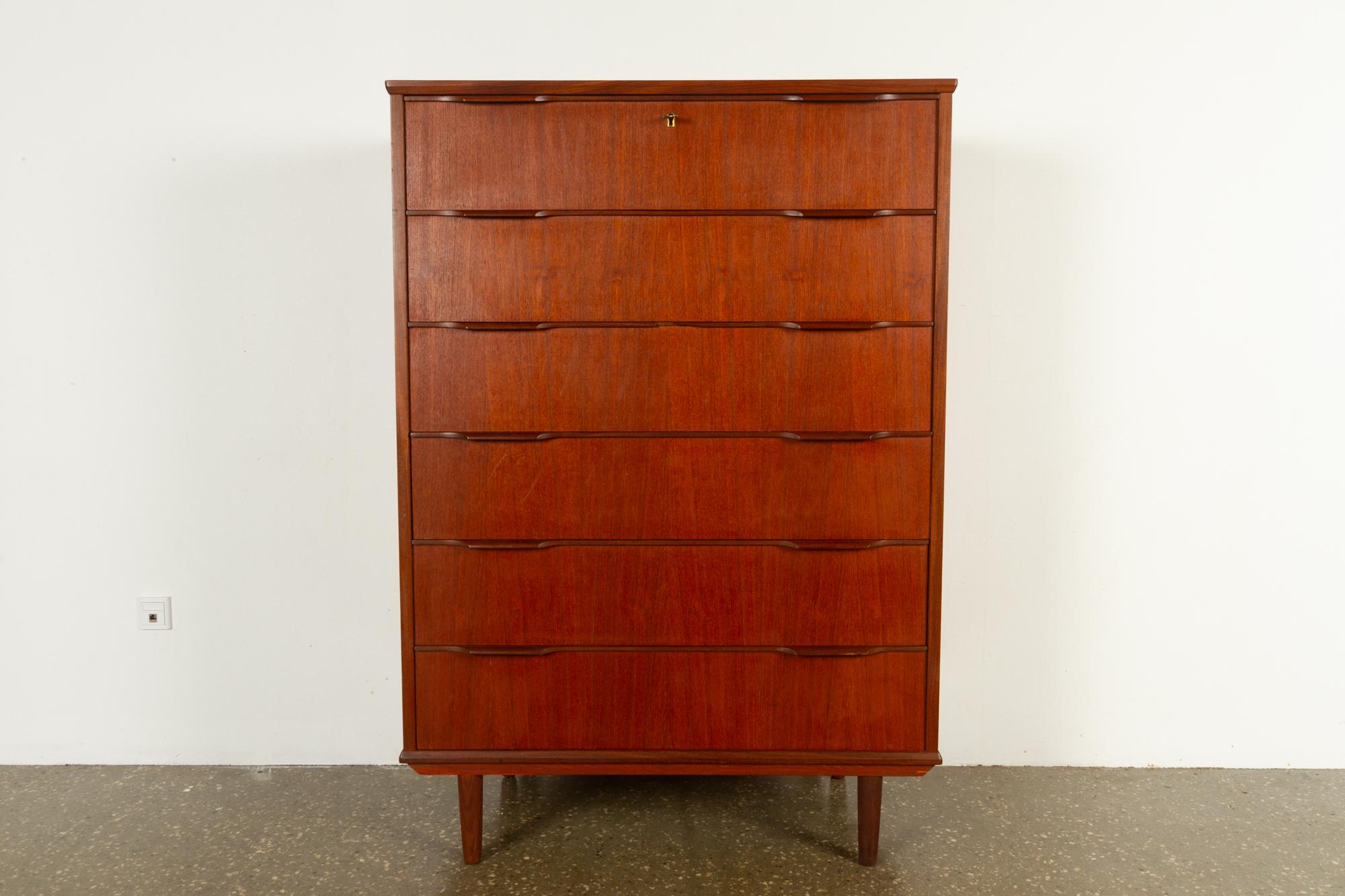 Large midcentury Danish teak dresser, 1960s
Vintage tallboy with six drawers and sculpted grips in solid teak. Top drawer has lock and key. Standing on four round tapered legs. 
Very versatile chest of drawers with loads of storage space.