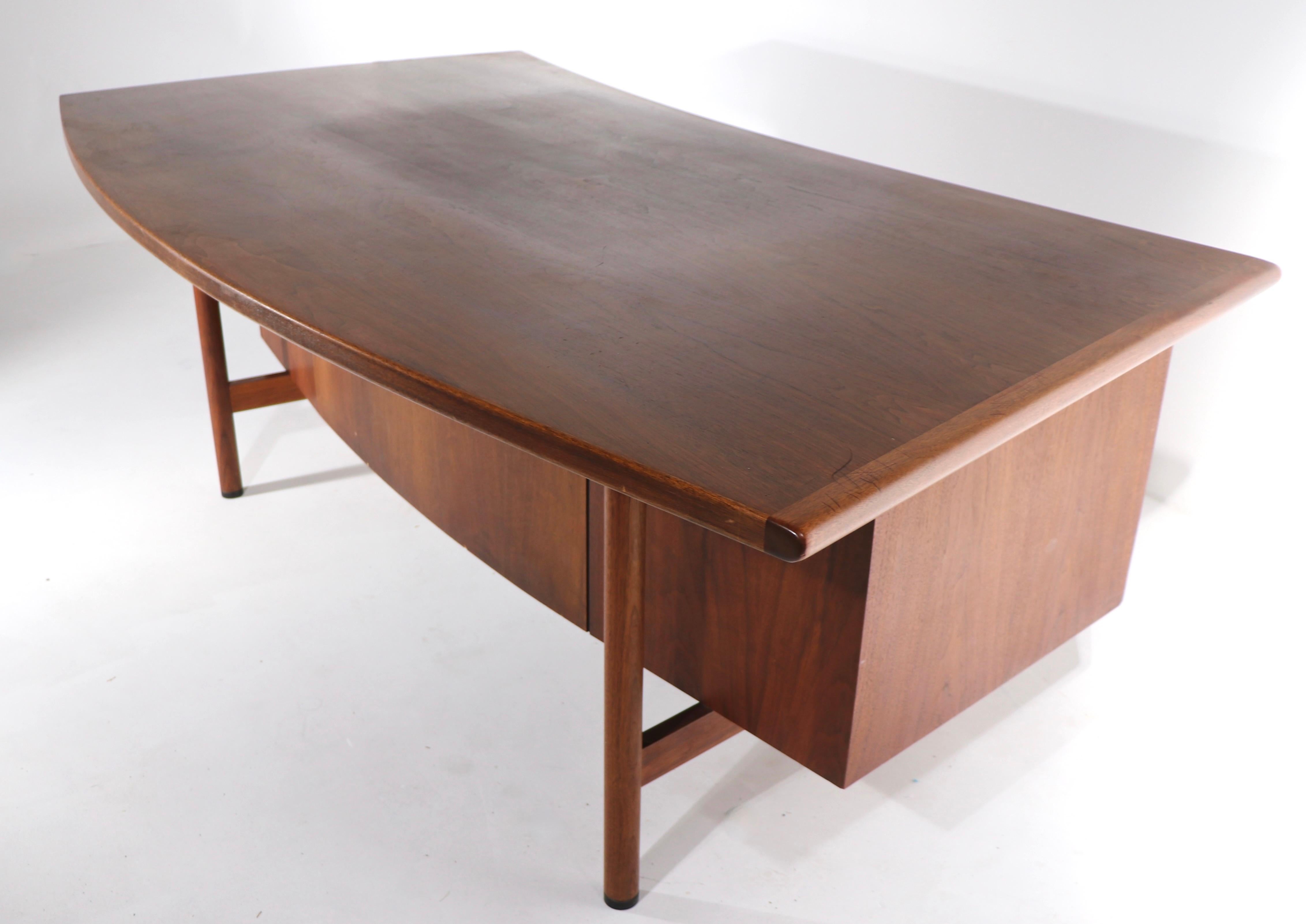 Spectacular Mid Century executive office desk having a curved semi circular top, that overhangs to allow pull up seating from both front and back. The desk also features two banks of drawers and a center pencil drawer, which creates ample storage