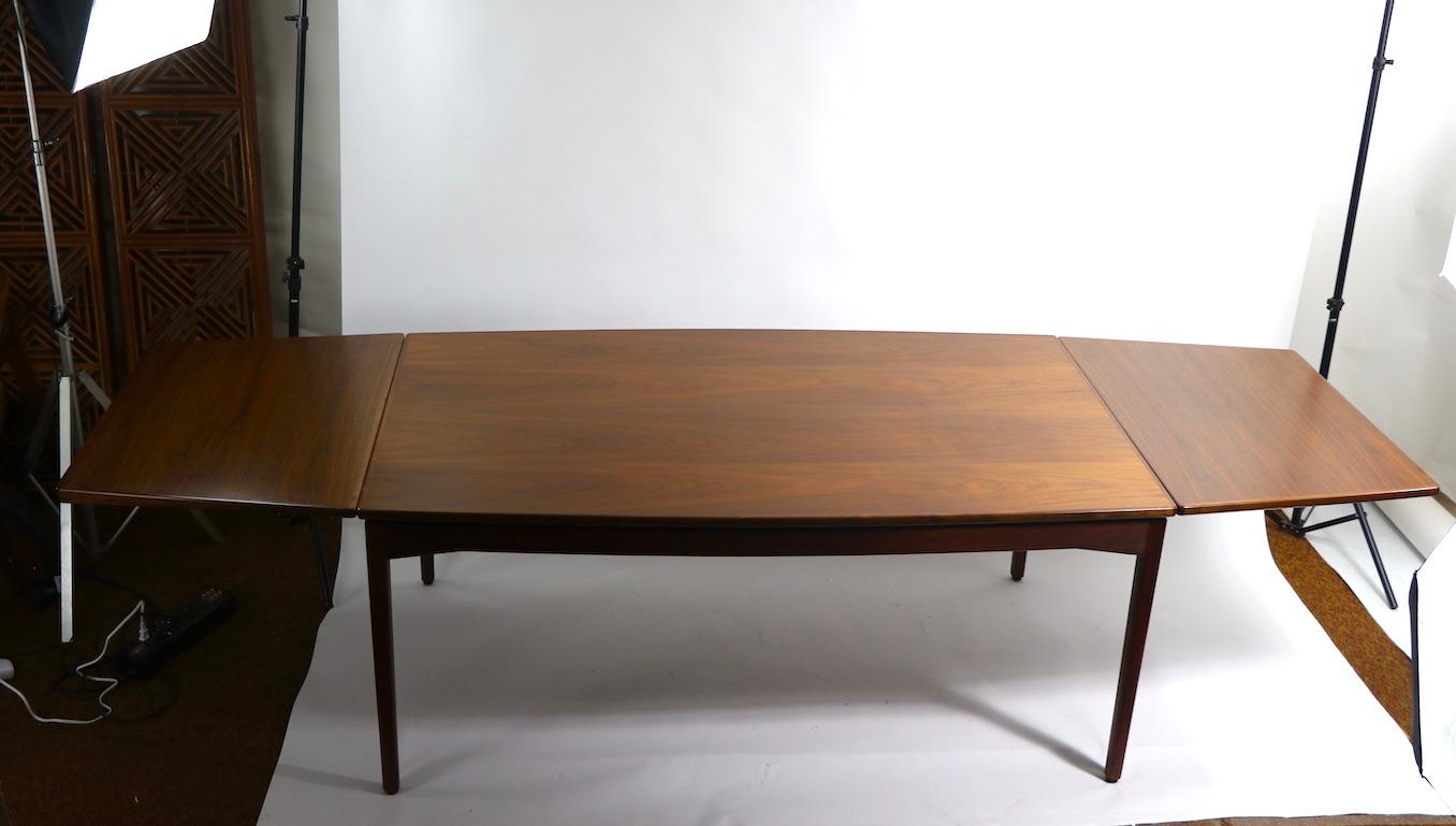 Stunning large scale dining table designed by Jens Risom for Jens Risom Design Inc.. The table has two refractory style leaves, which pull out from the narrow ends of the top, and store by tucking them under the top surface. The table top has been