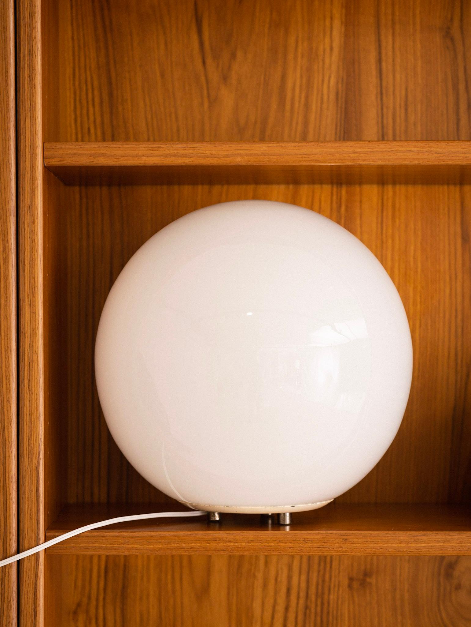 Mid-Century Modern glass globe table lamp. Glass glob sits upon a footed metal base.