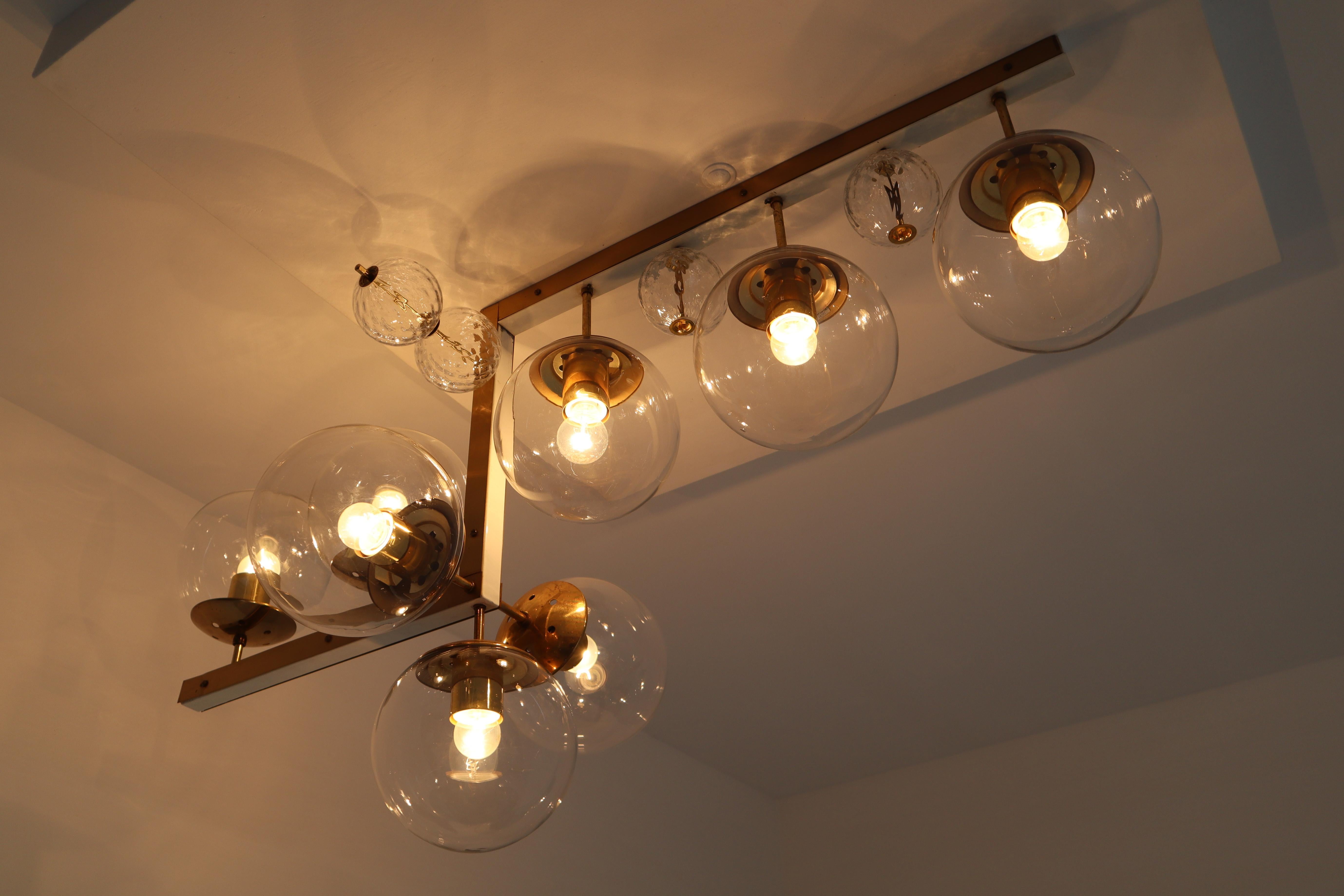 Large midcentury hotel light fixture in brass and hand blown glass, European, 1970s. This fixture is beautifully decorated thanks to the structured glass. The pleasant light it spreads is very atmospheric, this chandelier will contribute to a