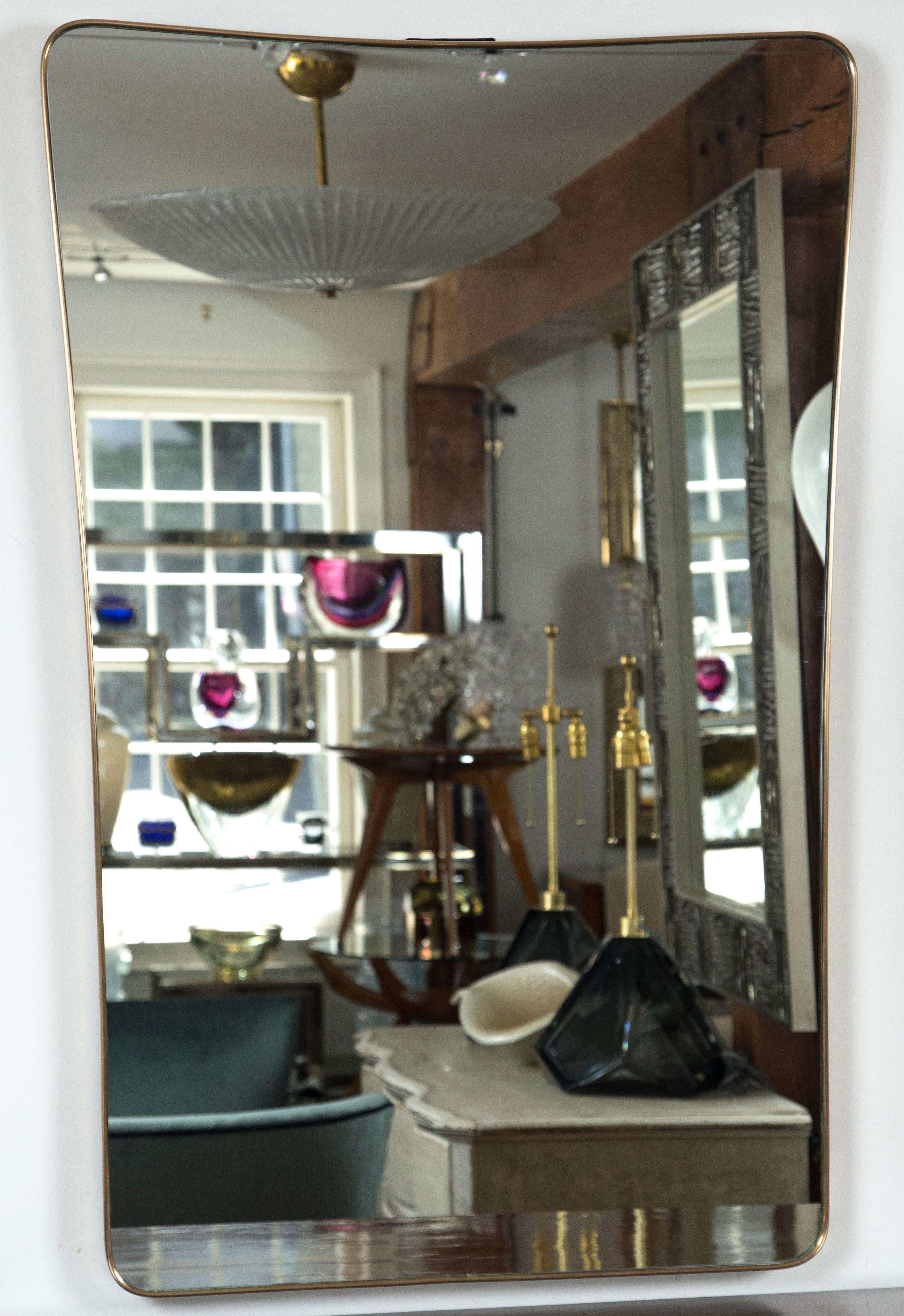 This midcentury Italian solid unlacquered brass mirror carries a very modified form of a shield shape form typical of early Gio Ponti mirrors. This is an early piece not a later reproduction.

Condition: Excellent, looking glass just replaced,