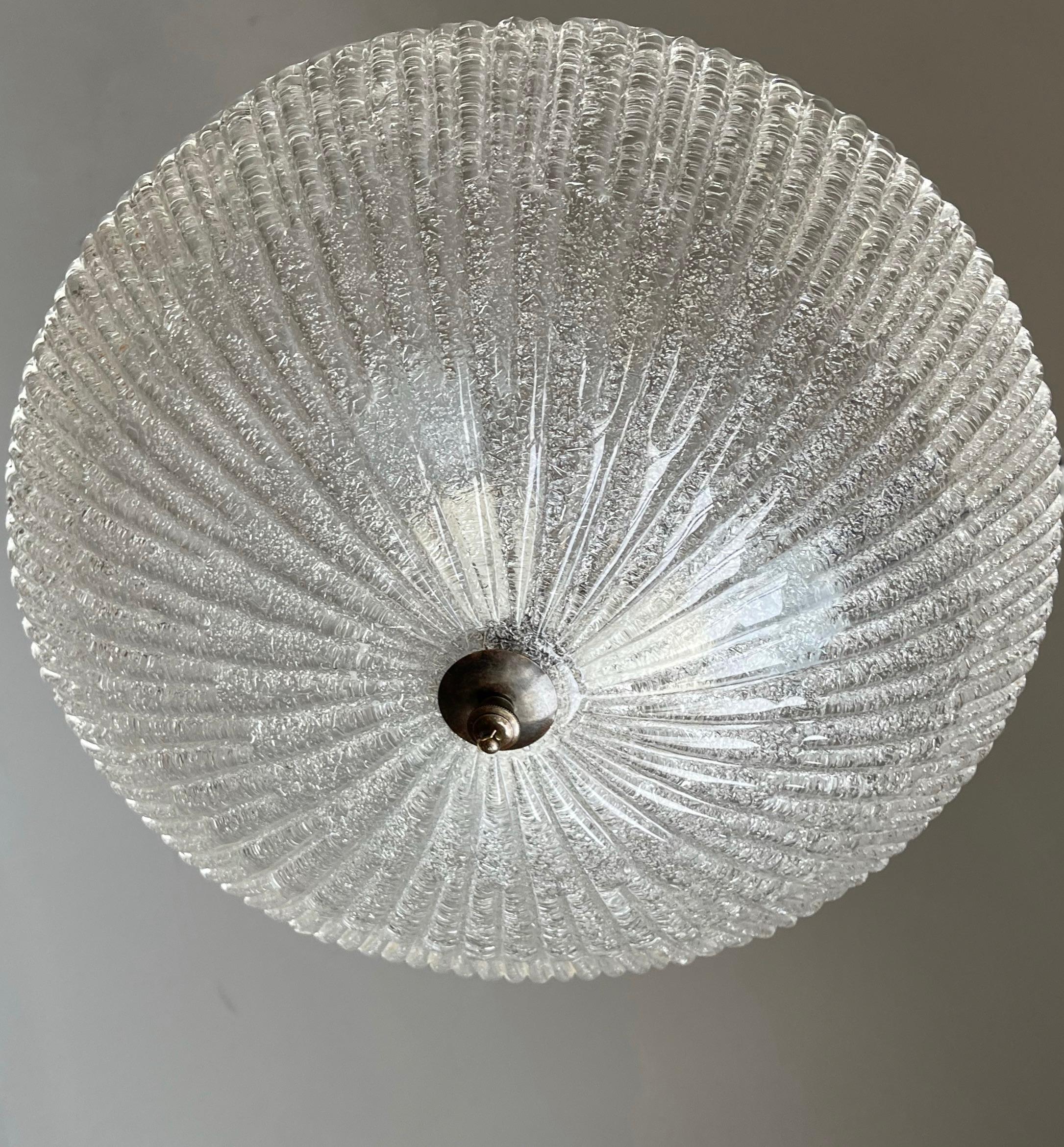 Large size, handcrafted clear glass Murano ceiling lamp.

This stylish Murano flushmount from the Midcentury era is of a unique design and the mouth blown glass shade is perfectly executed as well. You can use this sizeable glass flushmount with or