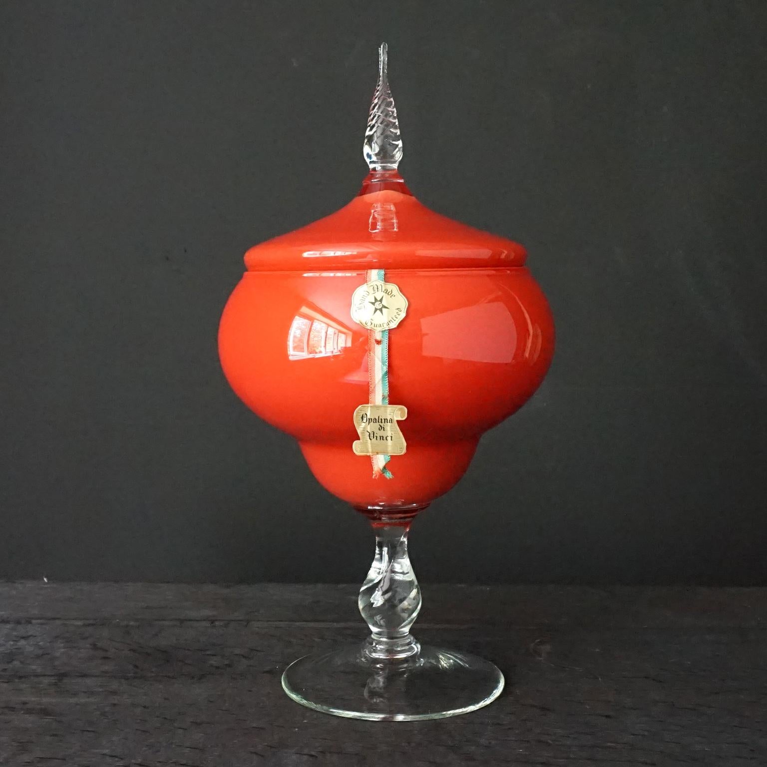 Large MCM Mid-Century-Modern Italian VNC Opalina di Vinci 2-layers cased glass candy or apothecary Jar in the most peculiar subdued bright tomato red colour I've ever seen. 
Usually cased glass has a layer of white, this jar hasn't. There are two