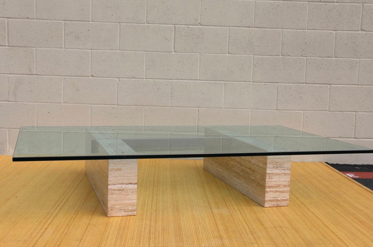 Spectacular Mid Century coffee table made in Italy from the 1970’s. It has been donde in two travertine bases and a rectangular glass top. It also has a chrome piece that crosses through the two travertine bases giving the table extra support for