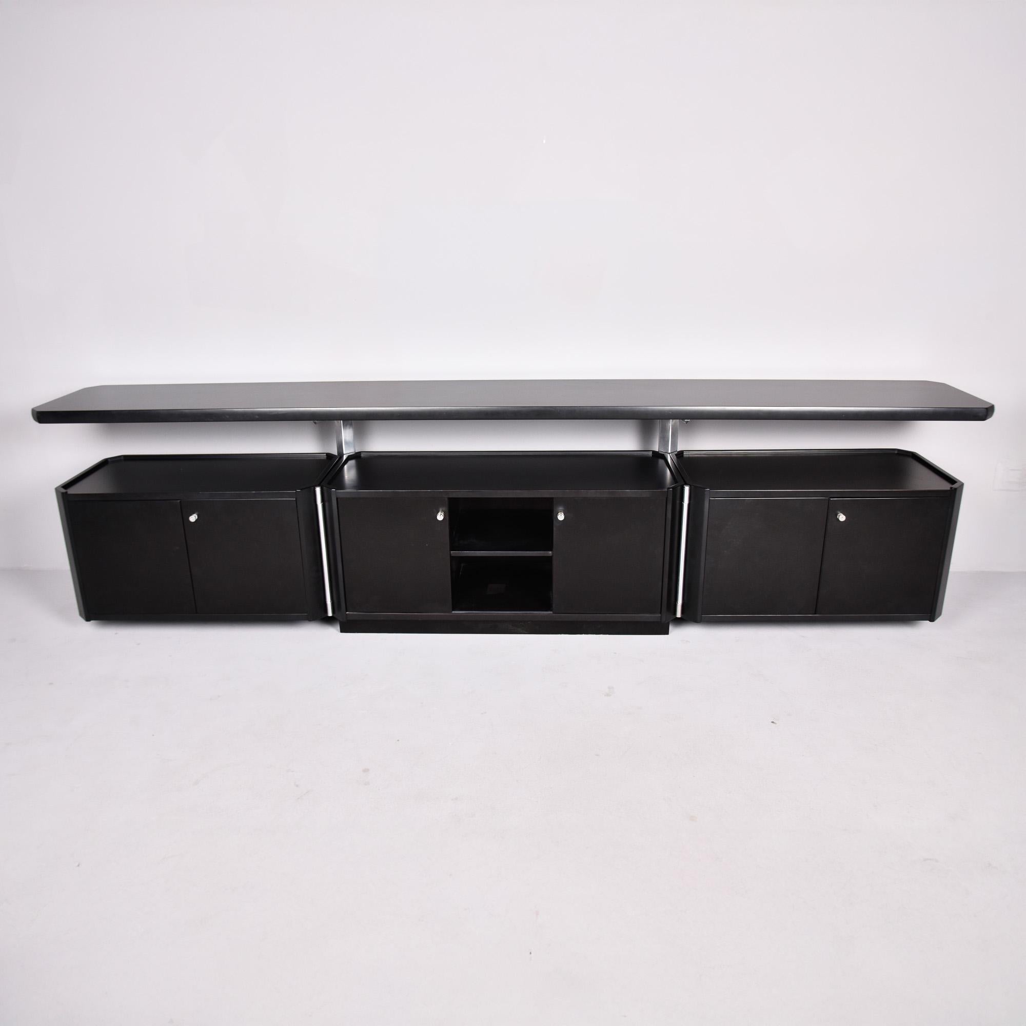  Encontrado en Italia, este gran aparador de la década de 1990 tiene un acabado negro y los herrajes son plateados, parece aluminio cepillado. La base del armario presenta una sección central con puertas correderas y una única balda interior,