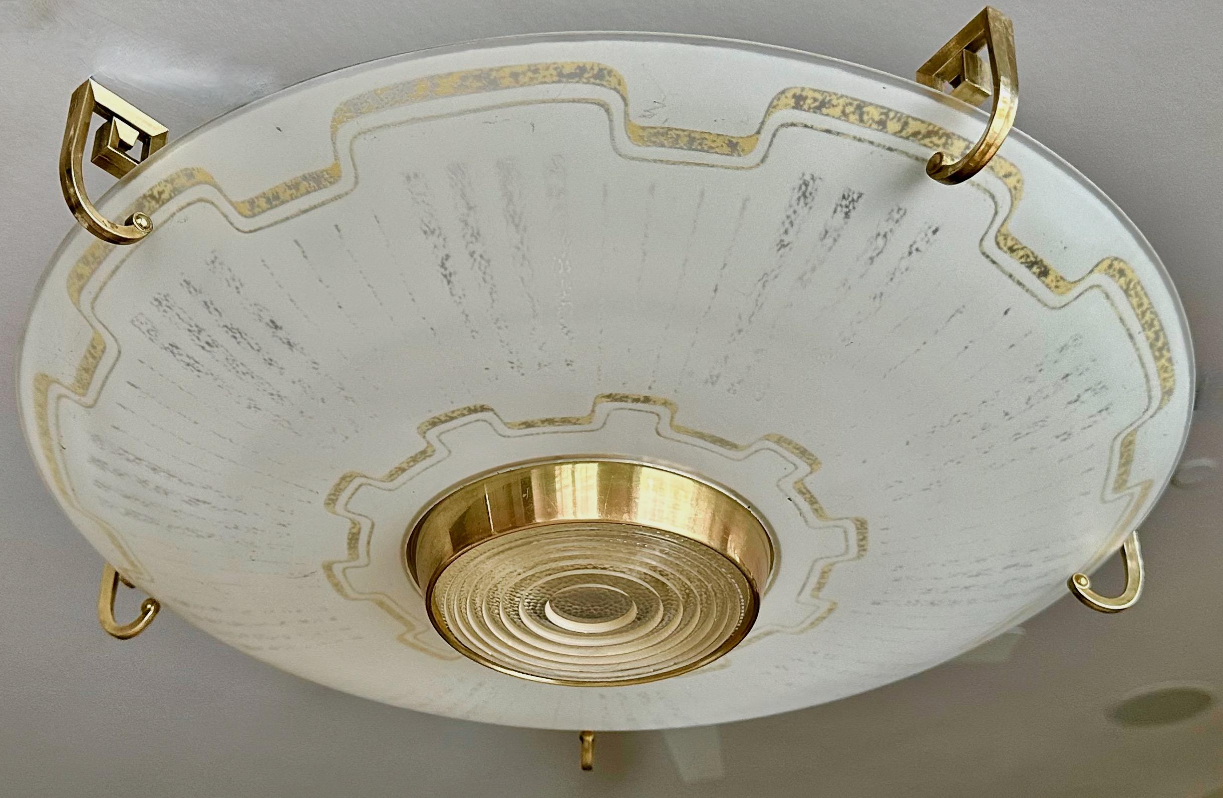 Una grande plafoniera a incasso da soffitto a forma di disco volante di Lightolier, con montatura a chiave greca in ottone e vetro curvo smaltato con macchie d'oro. Può contenere fino a 6 lampadine di dimensioni normali. 