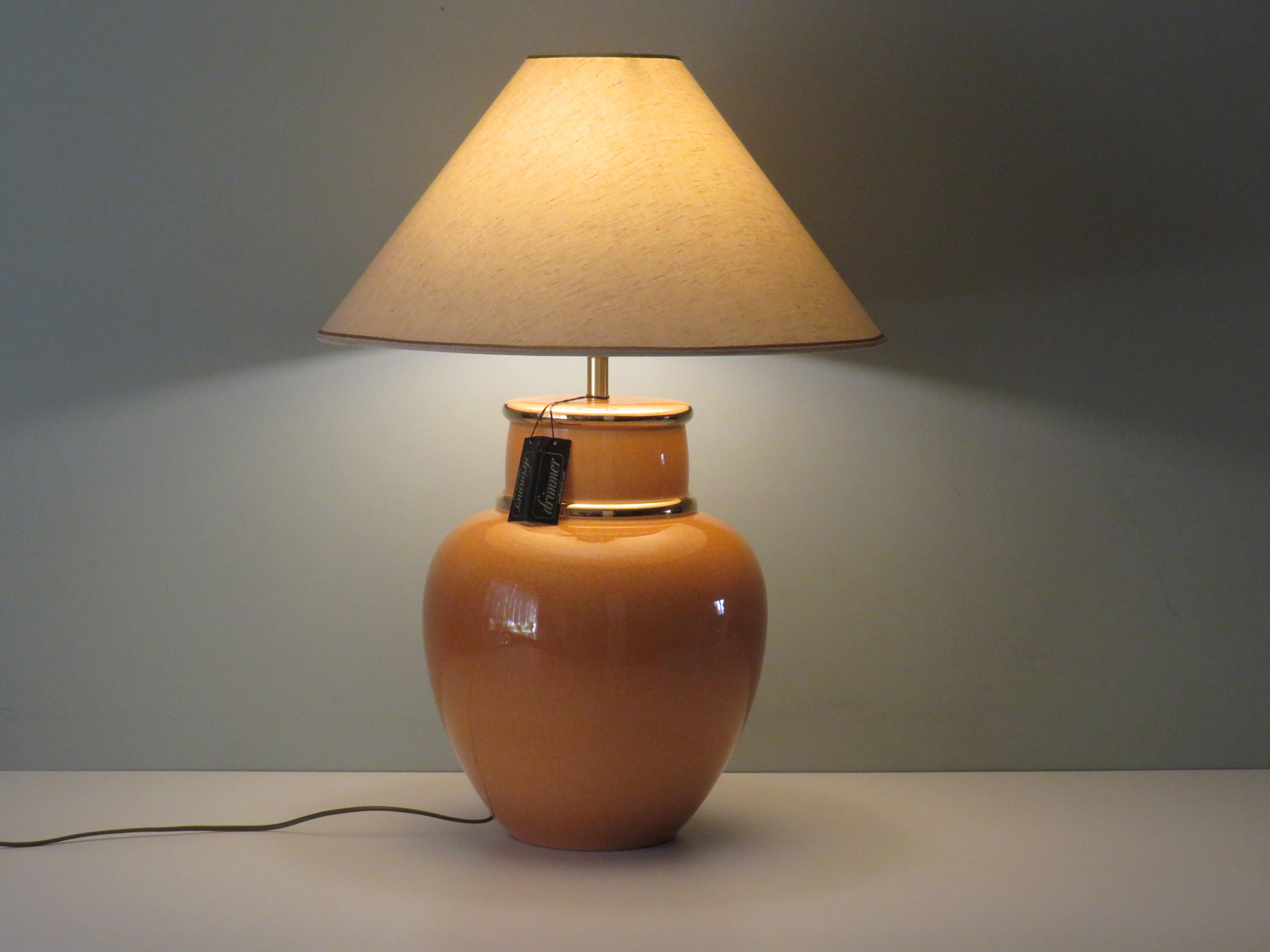 Base de lampe en céramique émaillée craquelée avec des accents dorés et l'abat-jour original en lin beige fini avec des bords dorés.
La base de la lampe est signée et étiquetée par Louis Drimmer.
La hauteur de la base de la lampe est de 51 cm et