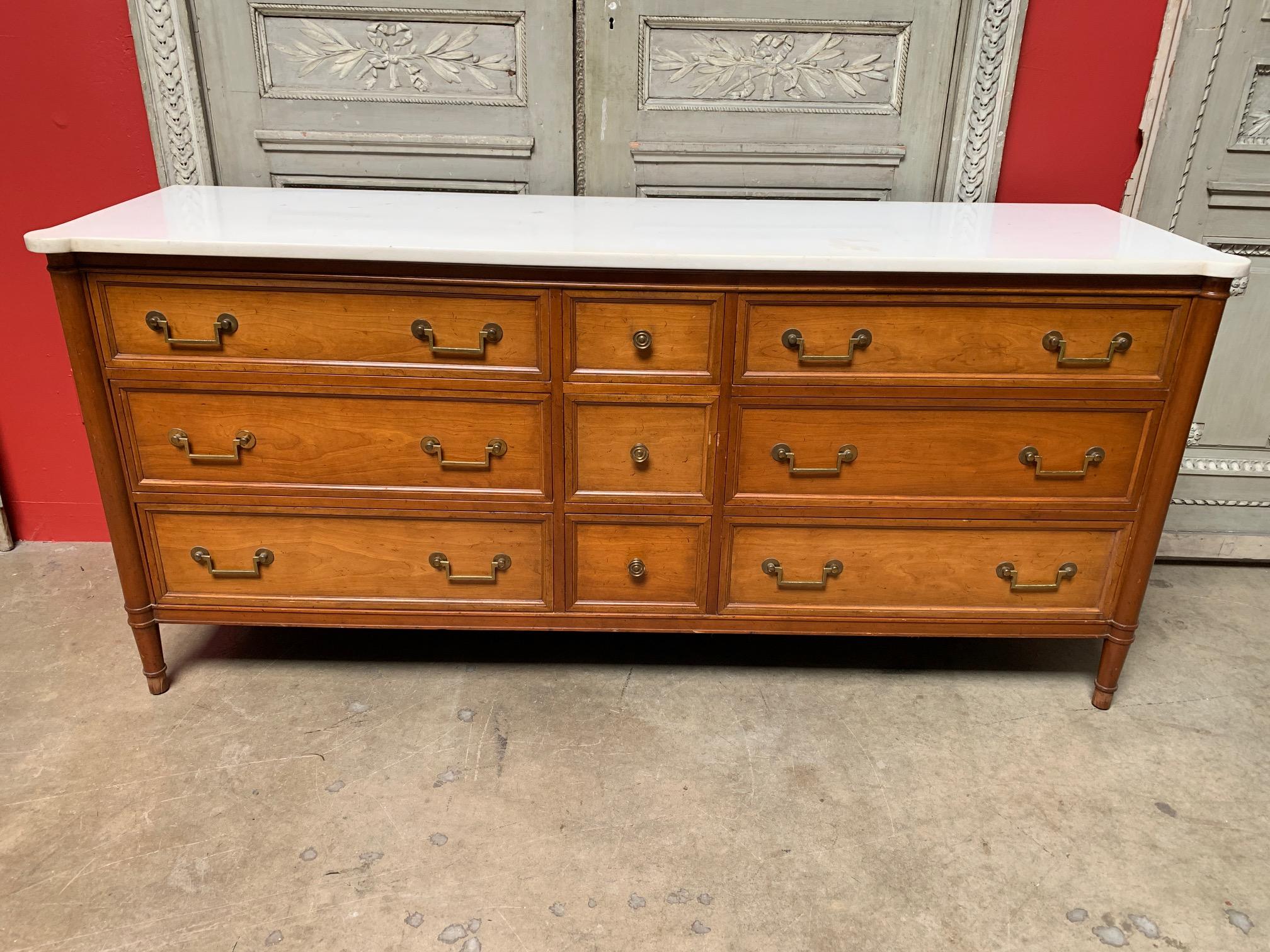 A nine-drawer mahogany double chest of drawers with a white marble top and brass hardware from Nahon Furniture.