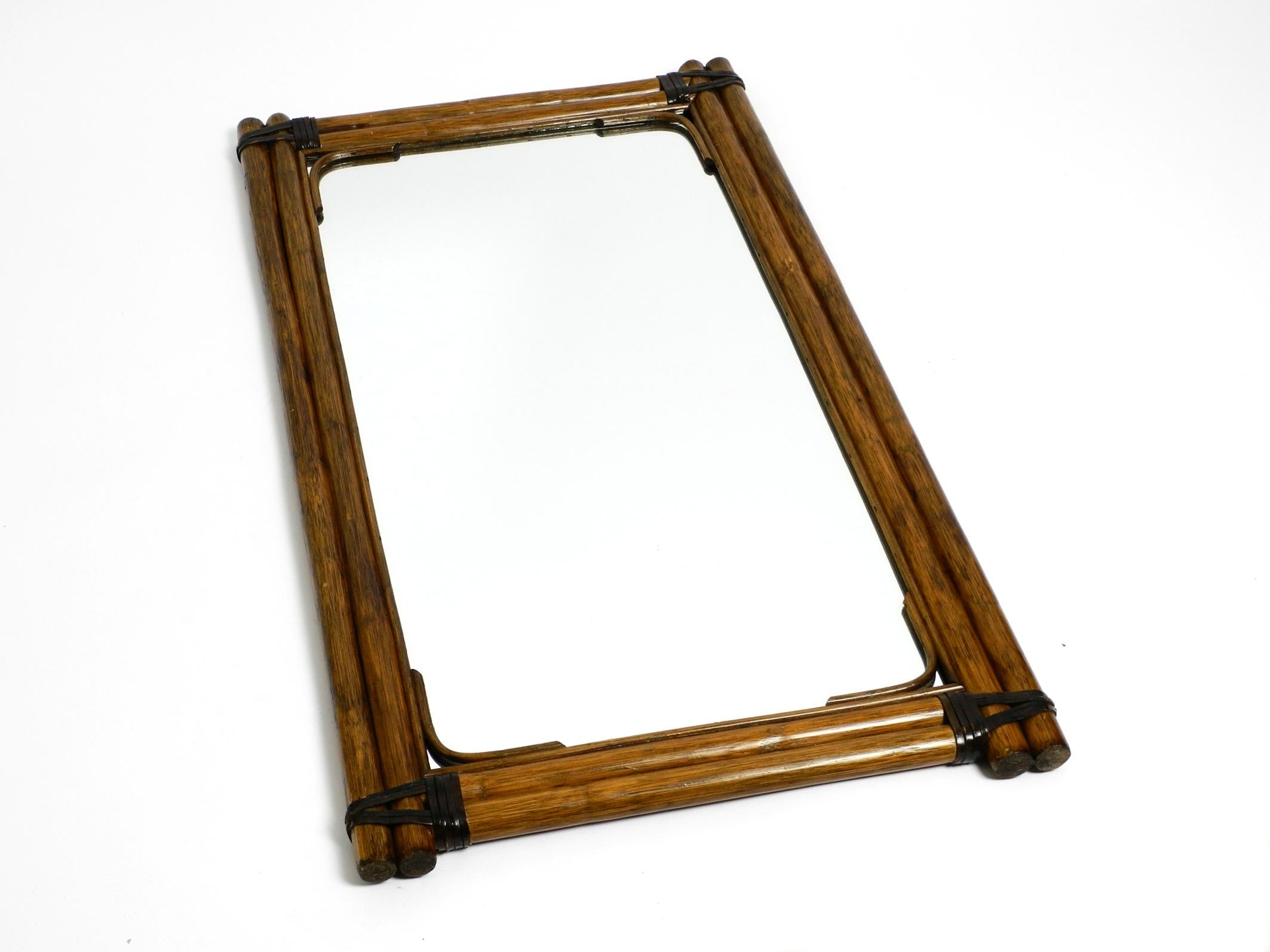Beautiful large Mid Century Modern wall mirror made of dark bamboo wood.
Made in Italy. Great Italian minimalist design of the 1950's.
The wood is additionally fastened at the corners with leather straps.
Looks very nice with the old patinated