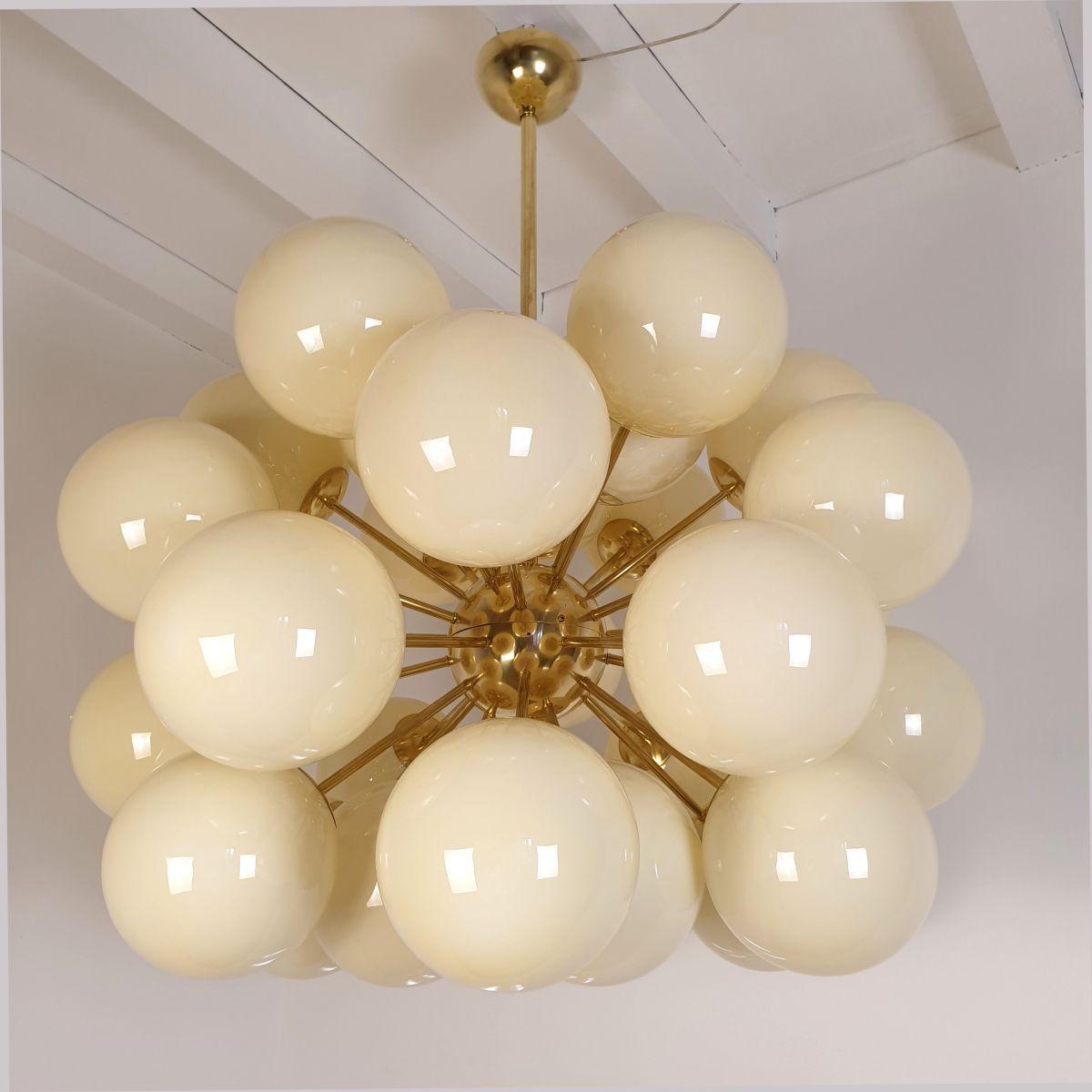 Very large Mid-Century Modern Beige Murano globes Sputnik chandelier, Italy circa 1990s.
The huge chandelier is made of brass mounts and 30 Murano glass globes, each nesting one light.
The glasses are translucent, in a pale amber or beige color.
The