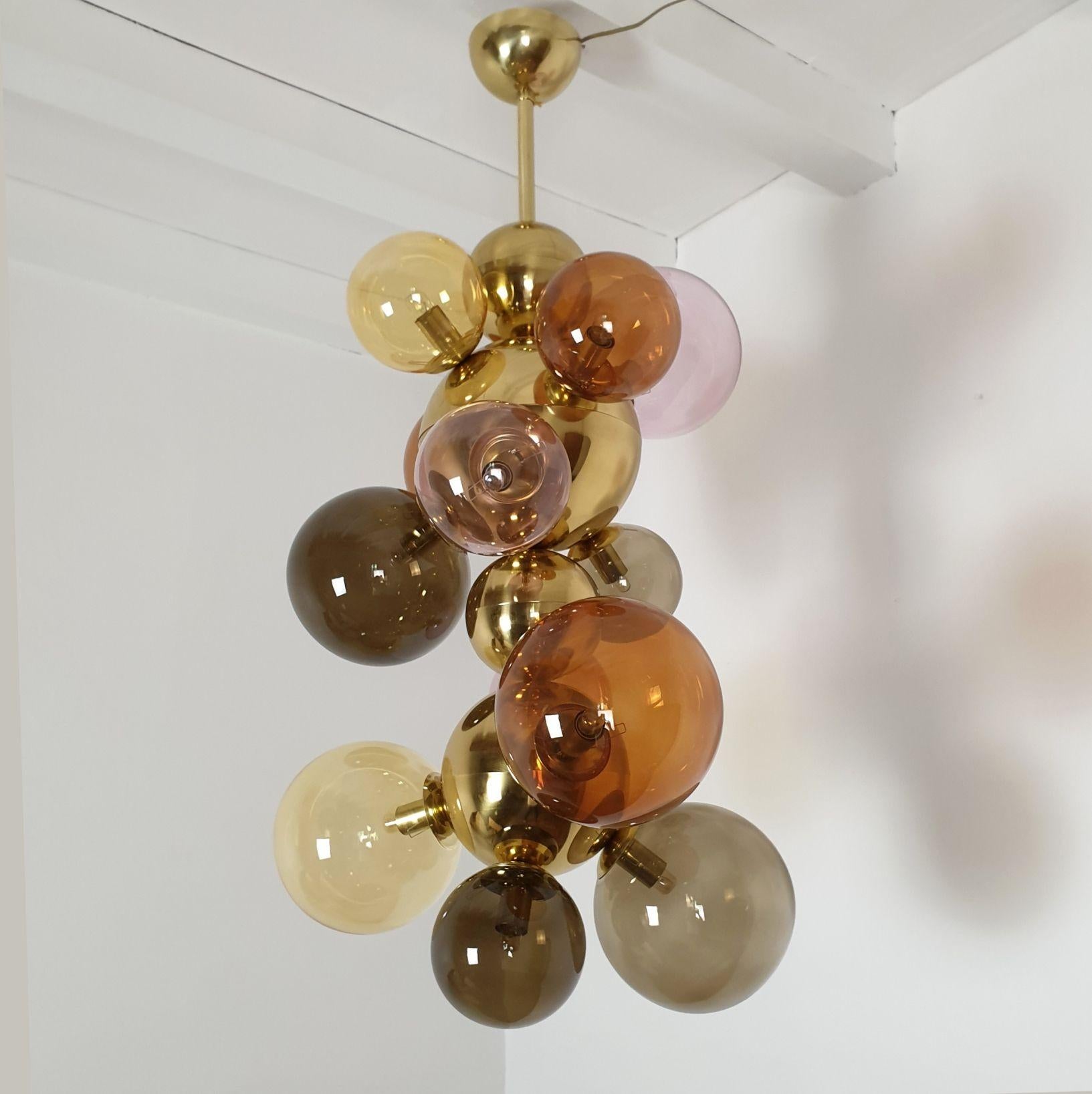 Large Mid Century Modern glass balls and brass chandelier or pendant light, Italy circa 2000s.
The chandelier is made of different sizes glass balls and polished brass balls and stem.
The glass balls are in different pastel colors: lilac, amber,