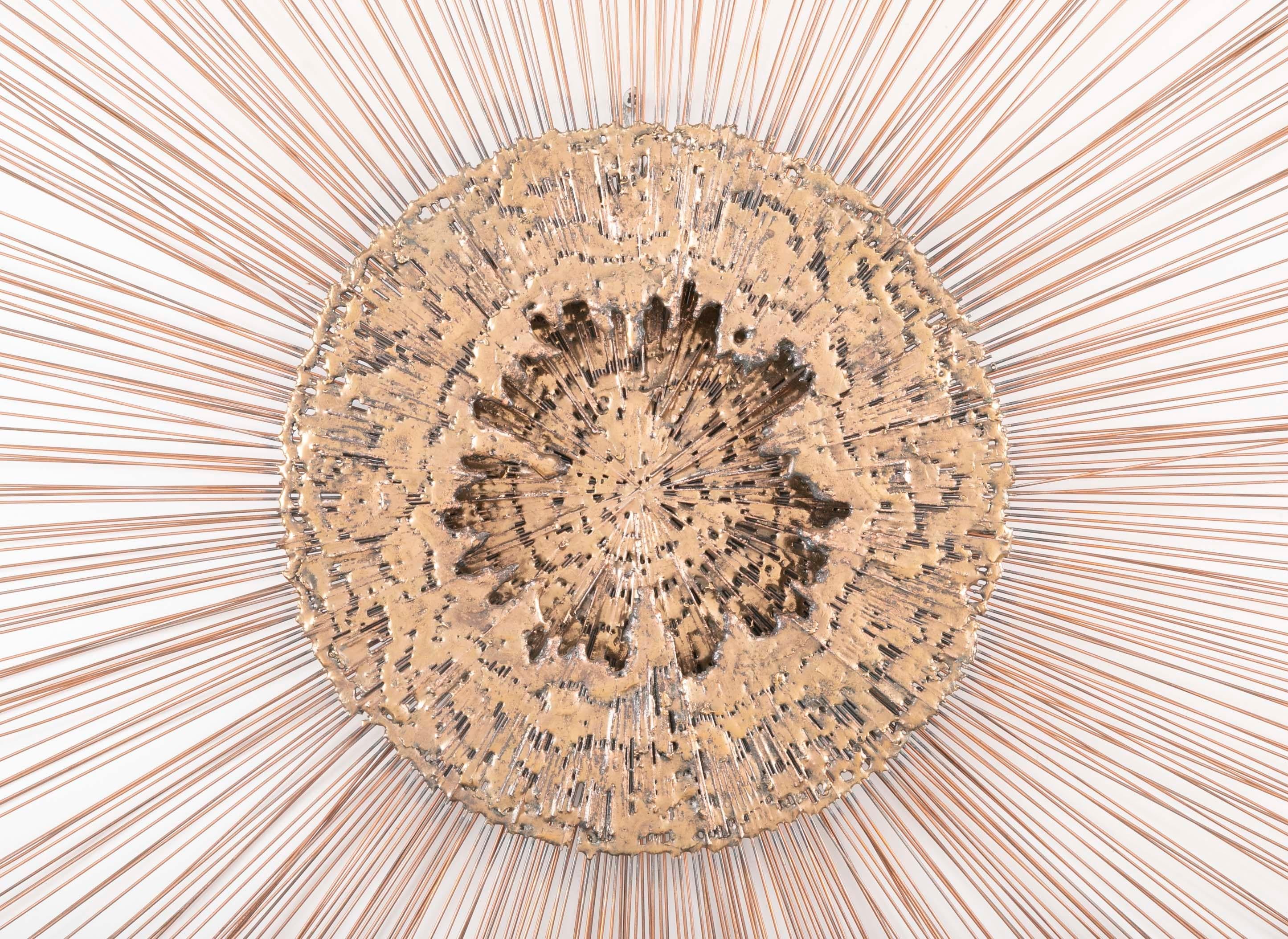 A stunning monumental 1970s starburst wall hanging with a textured 'molten' bronze central medallion surrounded by protruding copper rods. It brings to mind an exploding star, a supernova. Great scale at 42 inches diameter. In the style and of the