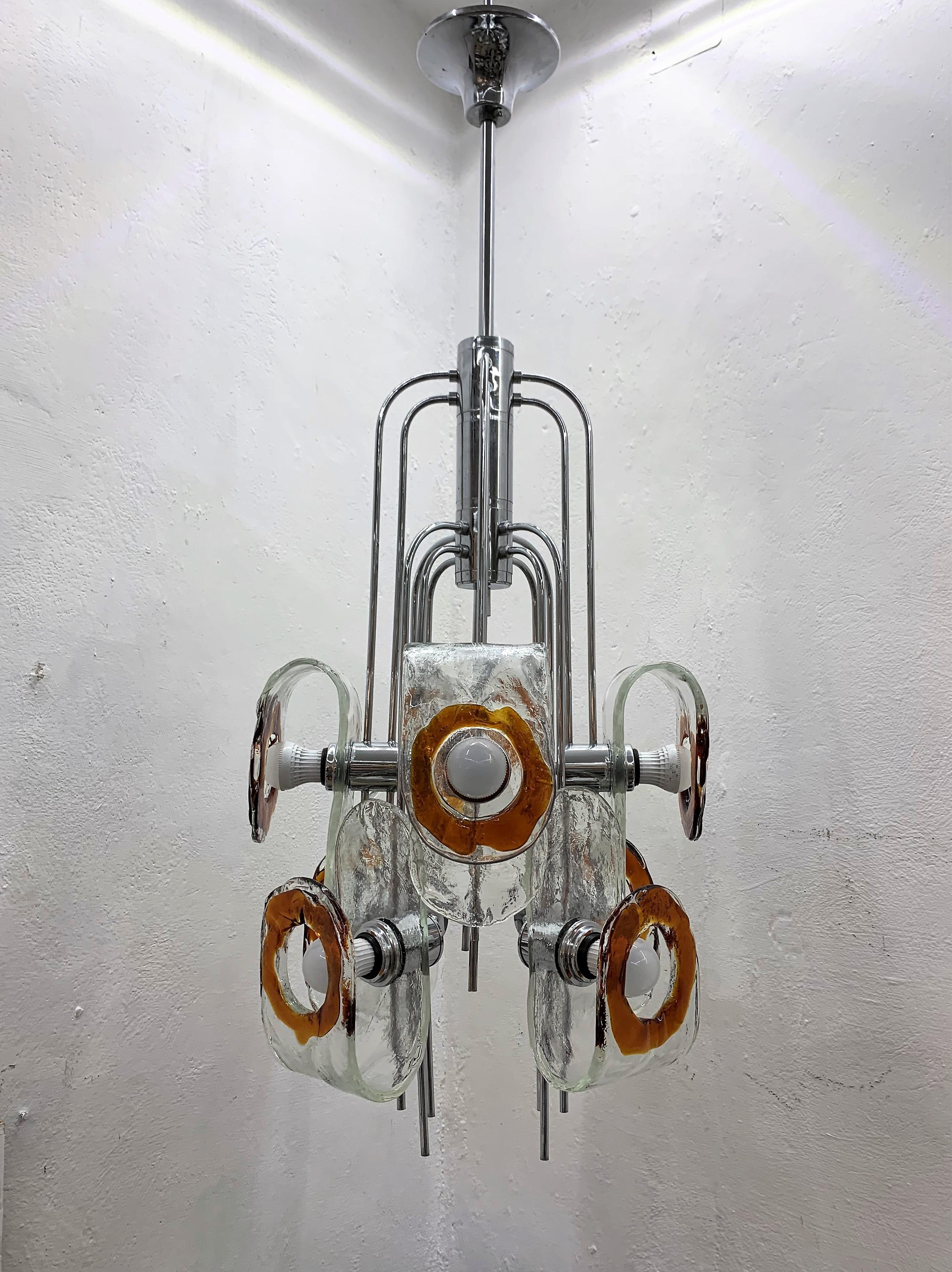 Large eight light Space Age chandelier manufactured in chromed hardware and hand blown orange and clear Murano glass by Mazzega.
The glass can be arranged in a few different ways as you can appreciate in a couple fo photos of the listing. 
These
