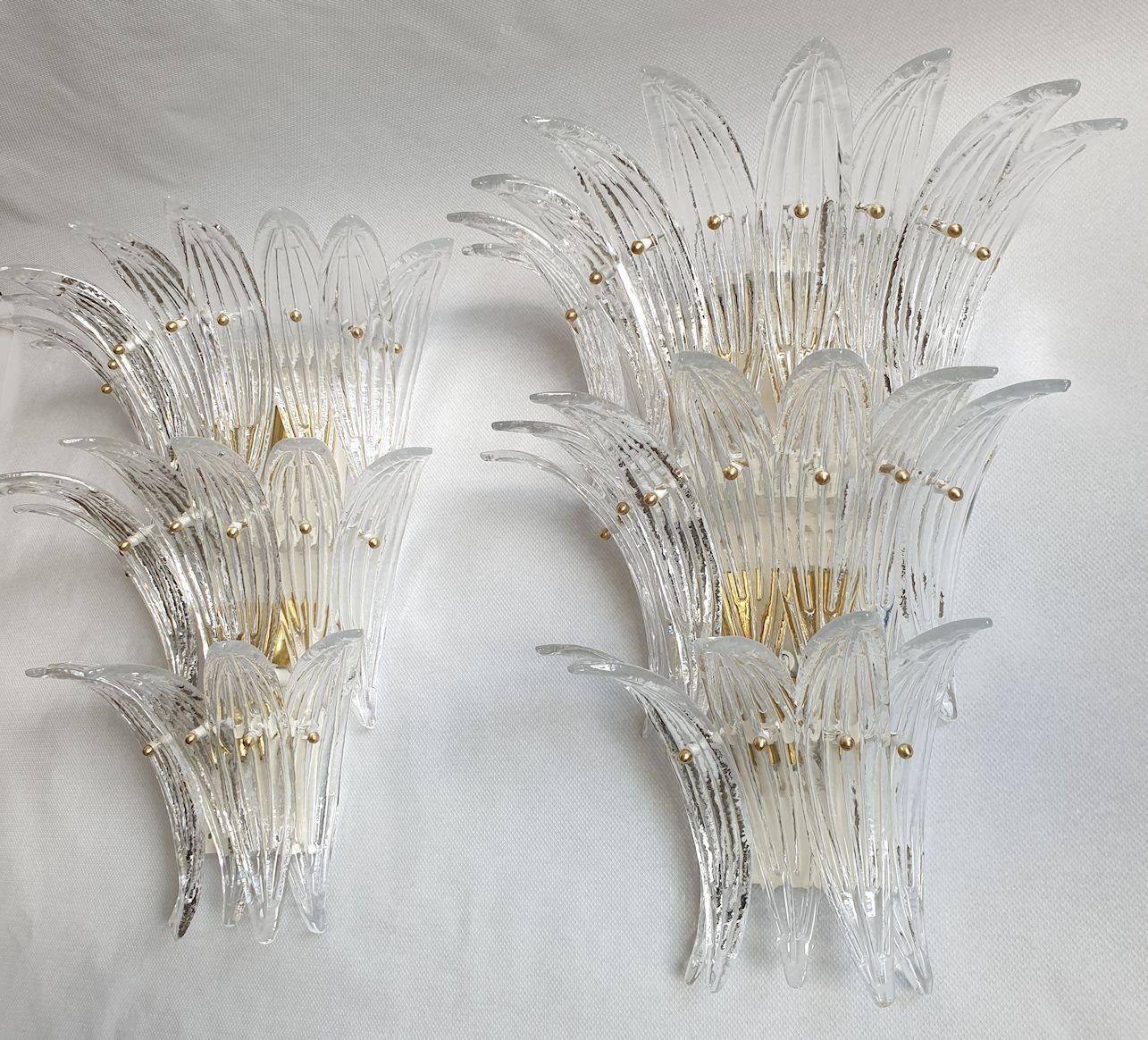 Pair of large Mid-Century Modern clear Murano glass Palmette sconces, Barovier and Toso style, Italy 1970s.
The large three tier sconces are made of 21 Palmette of handmade Murano glass each.
The back plate is painted white and it has with brass