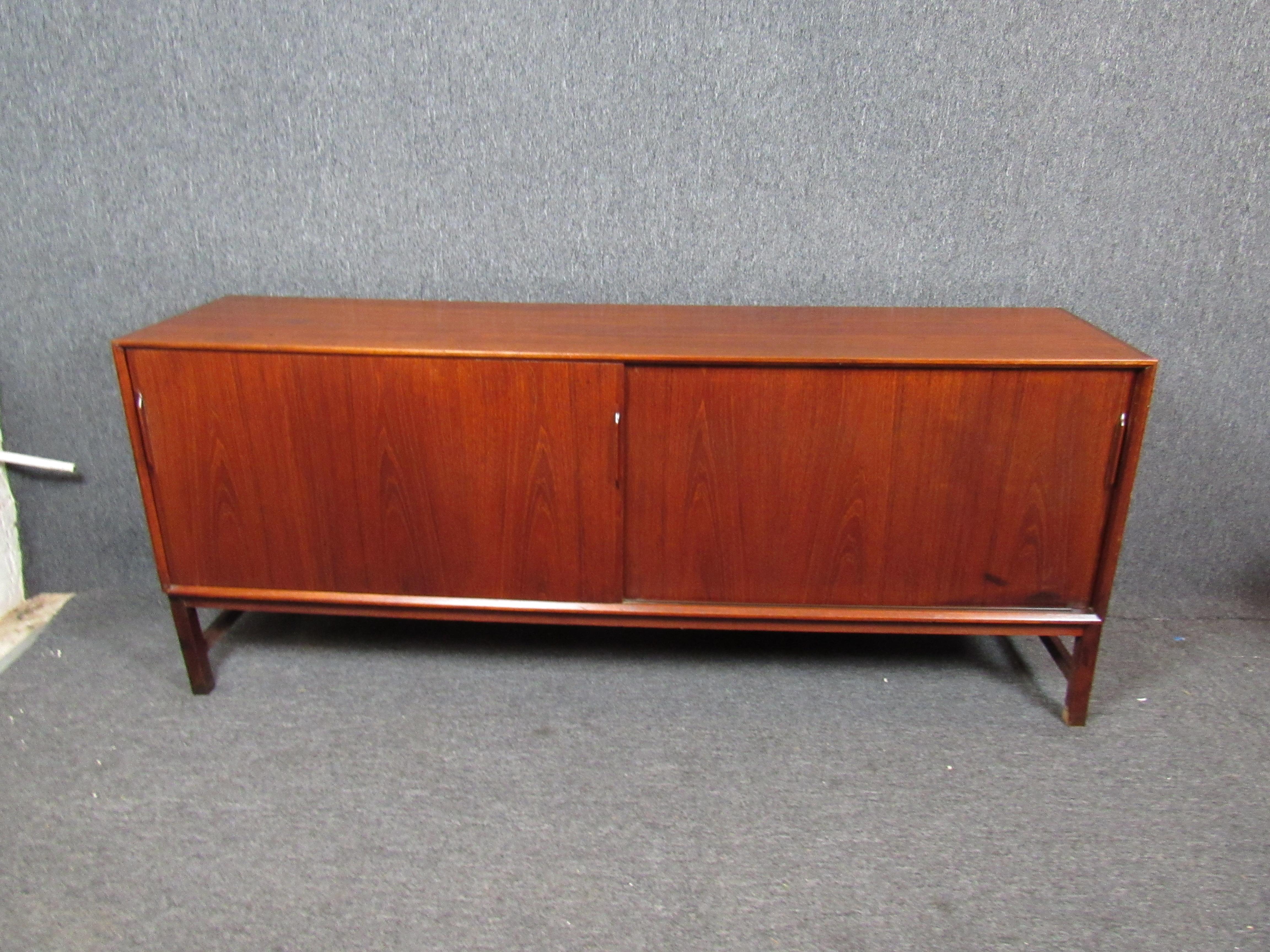 This Mid-Century Modern style credenza offers plenty of storage behind sliding doors, with multiple shelves and slide out trays. A rich woodgrain complements the credenza's minimal design and makes it a standout piece for any setting. Please confirm