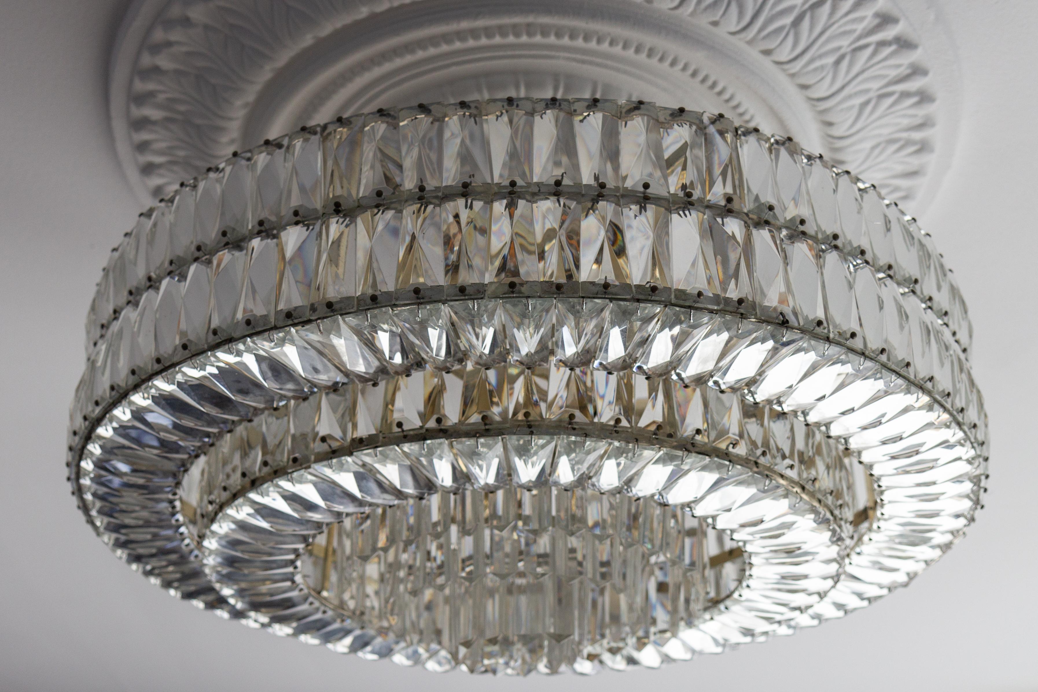 Large Mid-Century Modern crystal glass twelve-light ceiling light, Germany, circa the 1950s.
This impressive and large chandelier features a beautifully shaped crystal glass and chromed brass round body in tiers with twelve light points in two tiers