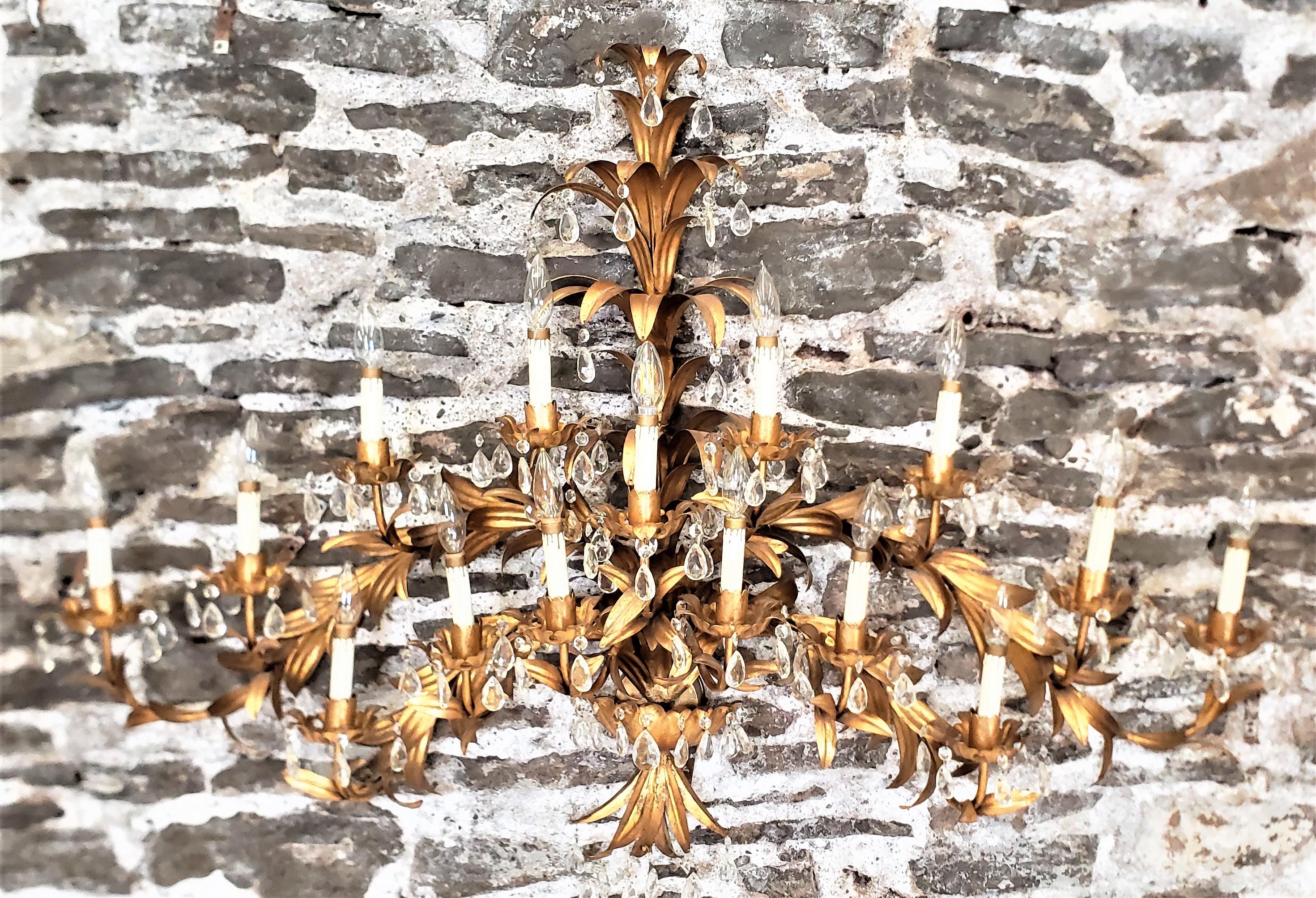 This very large and substantial wall sconce or sculpture has no maker's marks, but did originate from Italy and dates to approximately 1965 and done in a Hollywood Regency style. The sconce is composed of metal with a gilt finish that has been