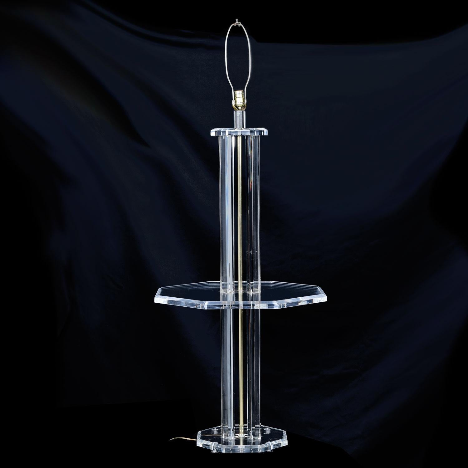 Large, heavy solid Lucite floor lamp with built in tabletop. Brass conduit runs the height of this acrylic lamp to supply power to the socket. Classic Mid-Century Modern and Hollywood Regency styles working in unison. 

(The measurements below