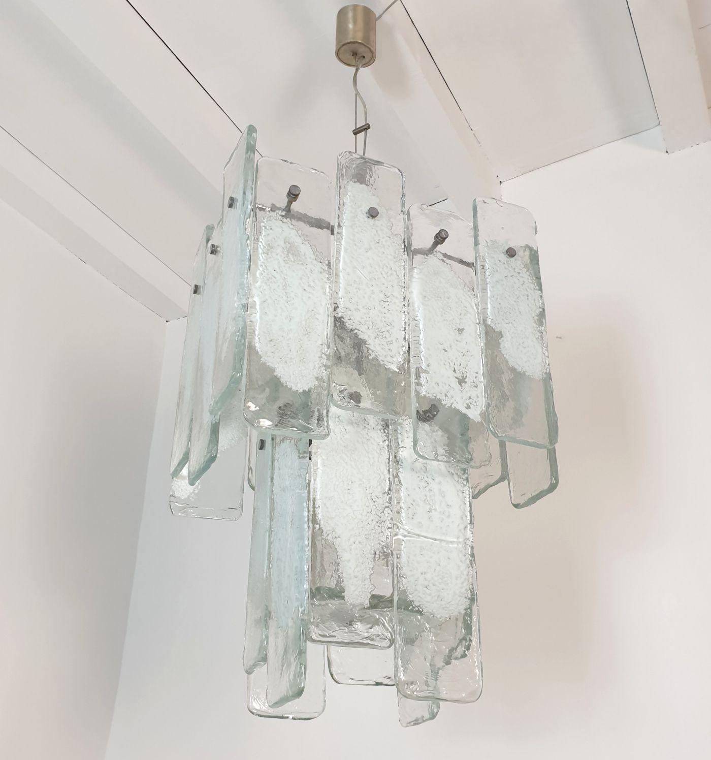 Large Mid Century Modern geometrical Murano glass chandelier by Mazzega, Italy 1970s.
The vintage pendant chandelier is made of a chrome frame and transparent and white Murano glass rectangular pieces.
The glass is thick with an irregular surface,