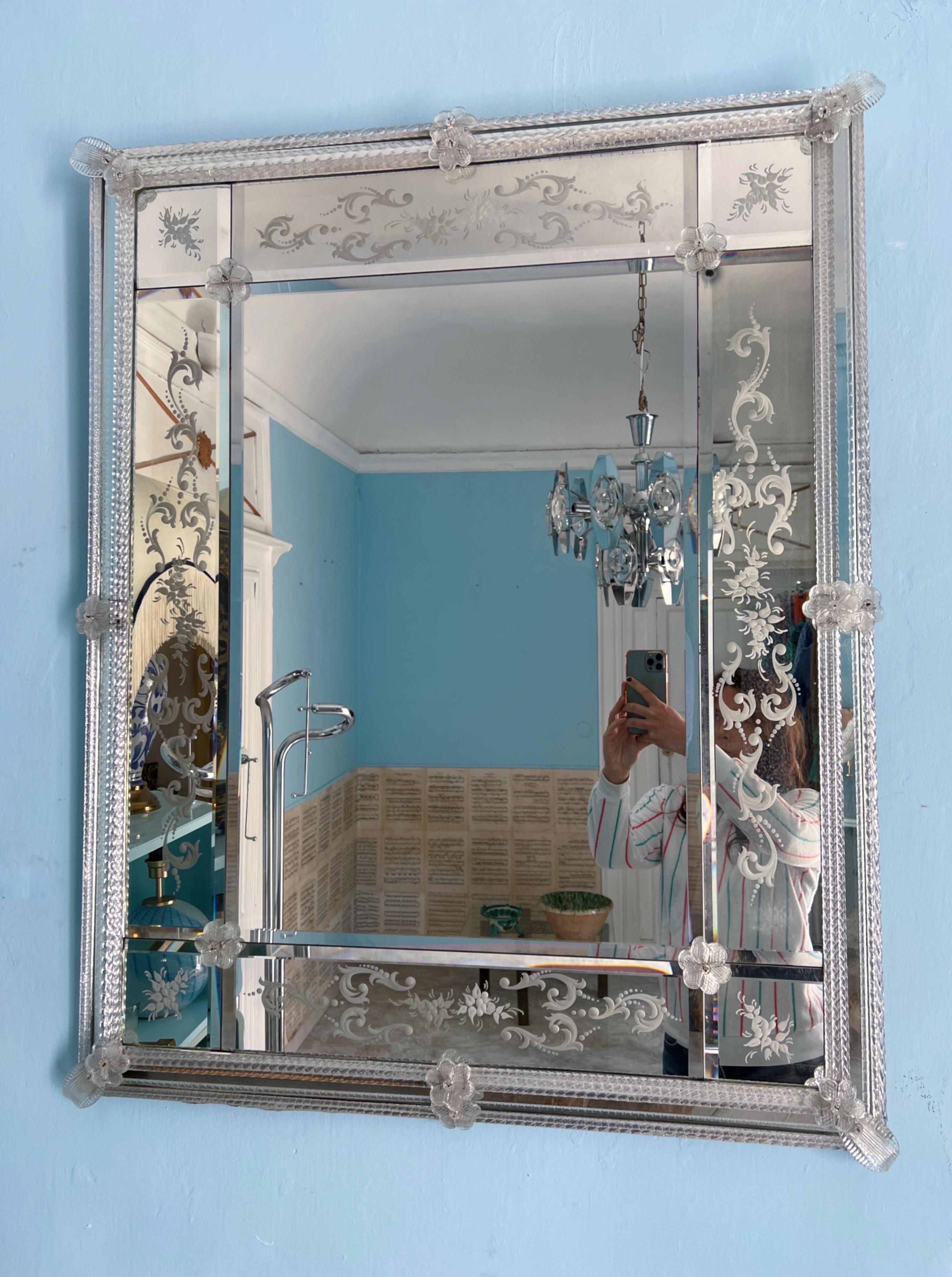 This magnificent Venetian mid-century wall mirror, crafted in the authentic Venetian style, hails from Murano in the 1980s. Its rectangular silhouette is embellished with a border composed of meticulously cut mirror tiles.

The frame is a tribute to