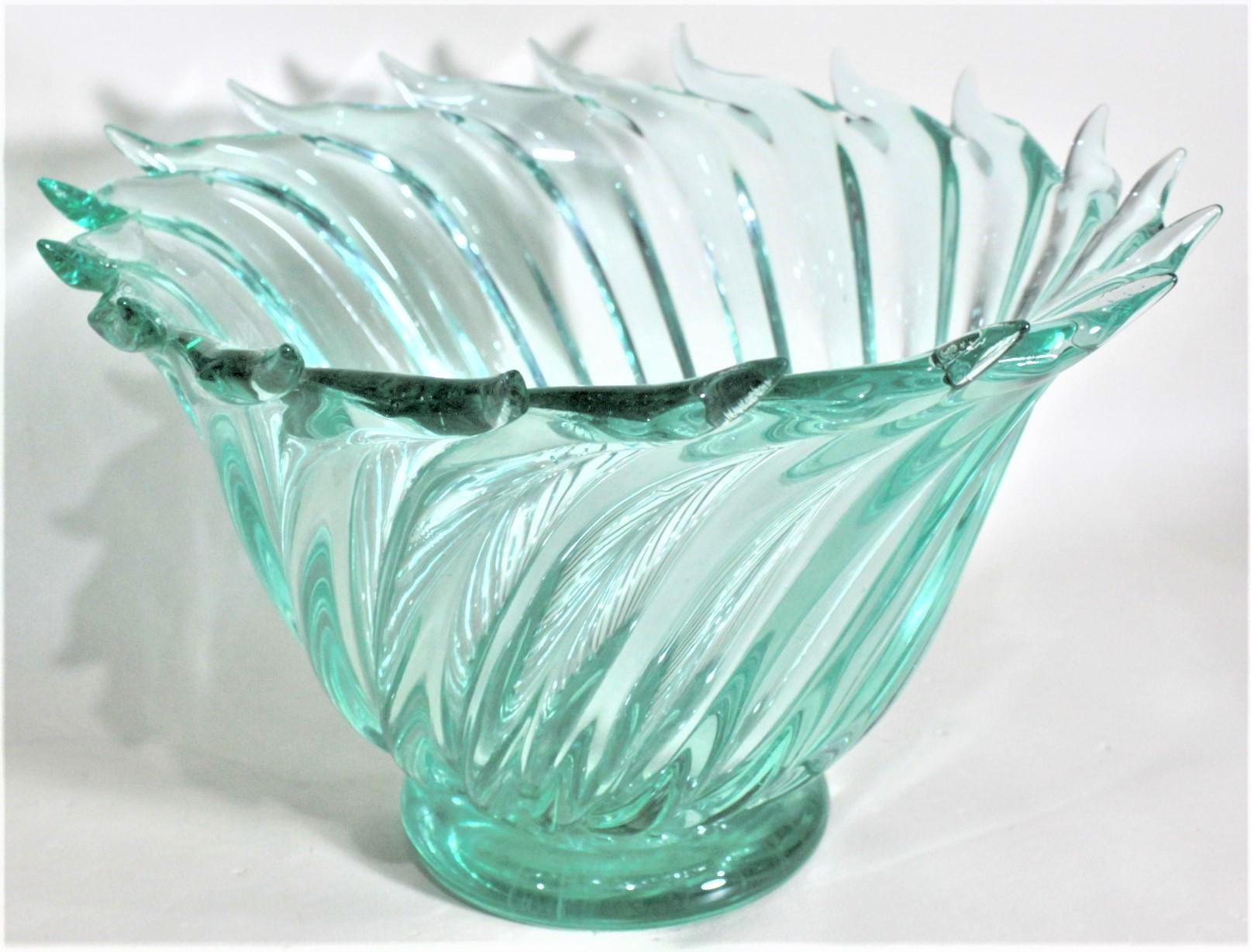 This large green Mid-Century Modern art glass swirled bowl was made in Murano Italy in circa 1965, and very likely by the renowned glass artist Ercole Barovier. The bowl is a series of swirled deep green glass that has been crafted in a serpentine