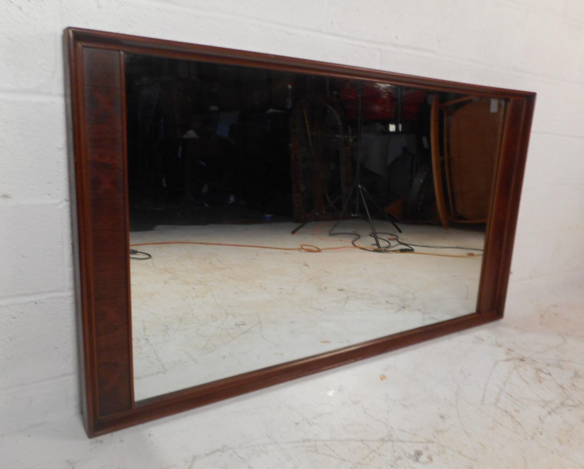 This impressive vintage modern mirror features a two-tone design with rosewood and walnut wood. A beautiful rectangular mirror that can be placed on the back of a dresser or hung on the wall. The unique raised and beveled edges make this mirror
