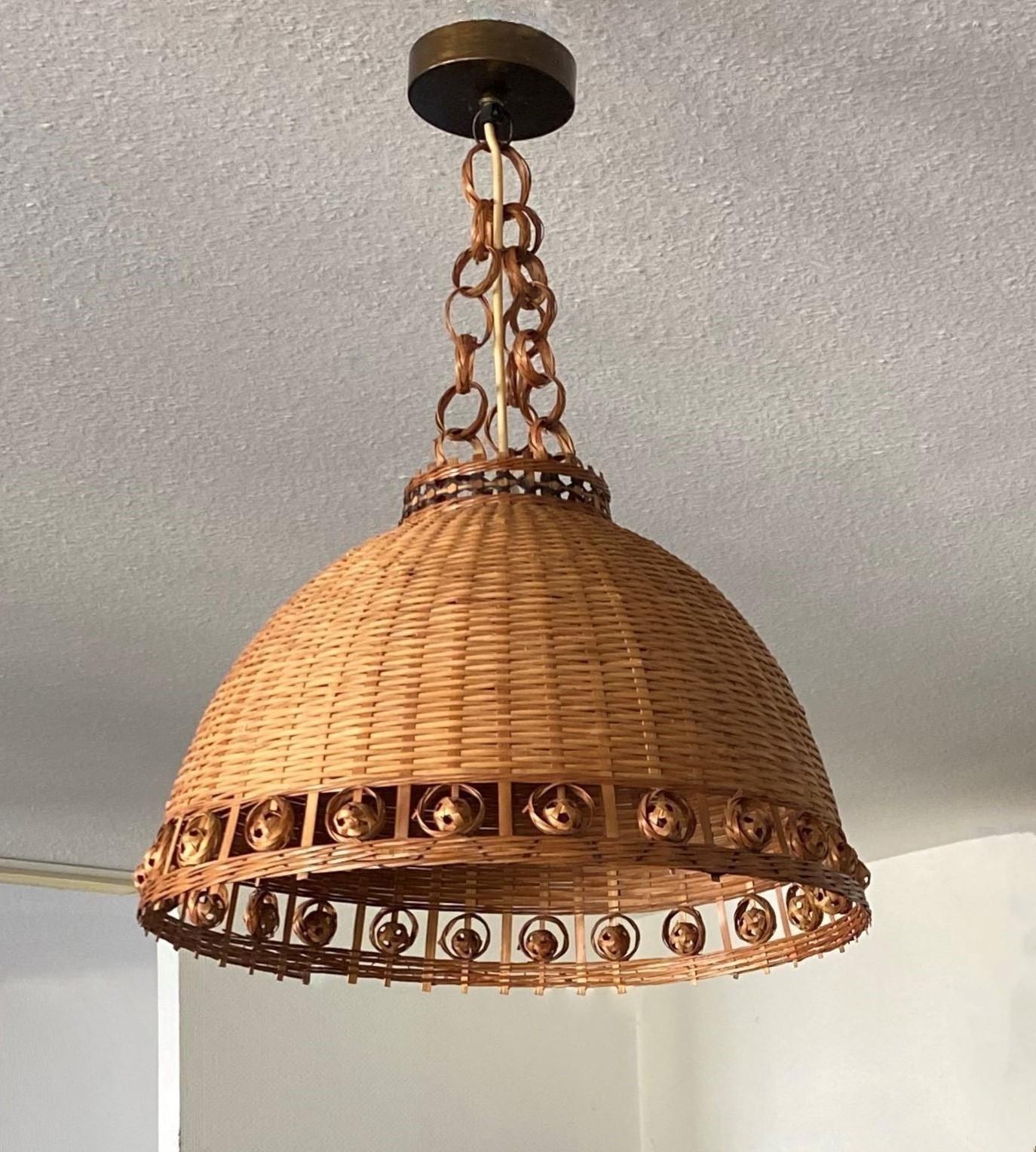 A lovely vintage Scandinavian hand-woven wicker pendant, Denmark, 1960s. This suspension light is entirely handcrafted in wicker beautifuly decorate with a border made of wicker small balls, hanging with triple chain of wicker rings, brass canopy. A