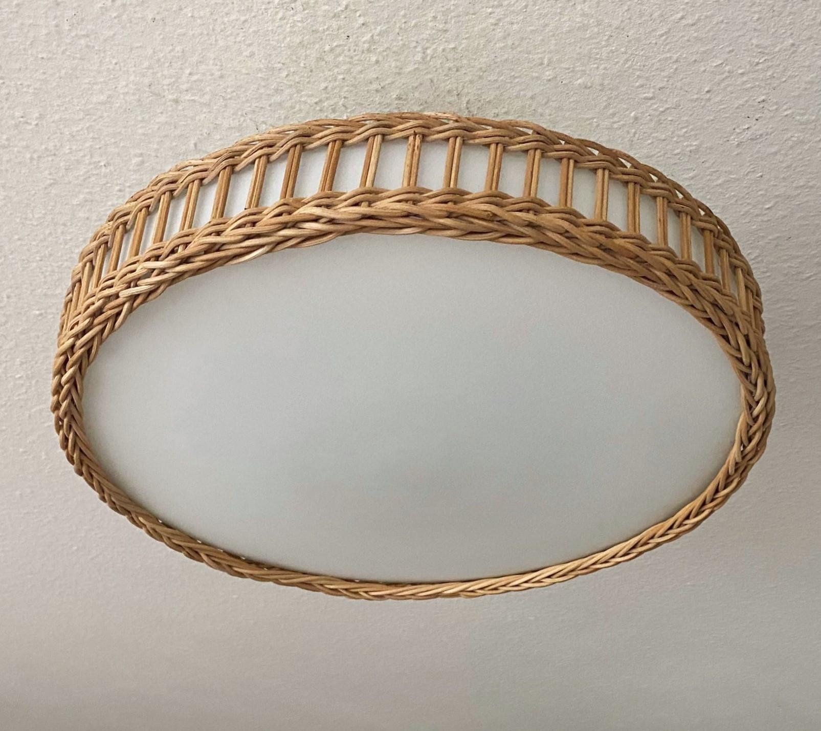 A large, rare Mid-Century Modern Scandinavian design two-light flush mount, 1960s, woven wicker basket around a large milk glass diffuser. This beaufiful piece is in very good vintage condition, no damages, rewired. It takes two E27 srew bulbs up to