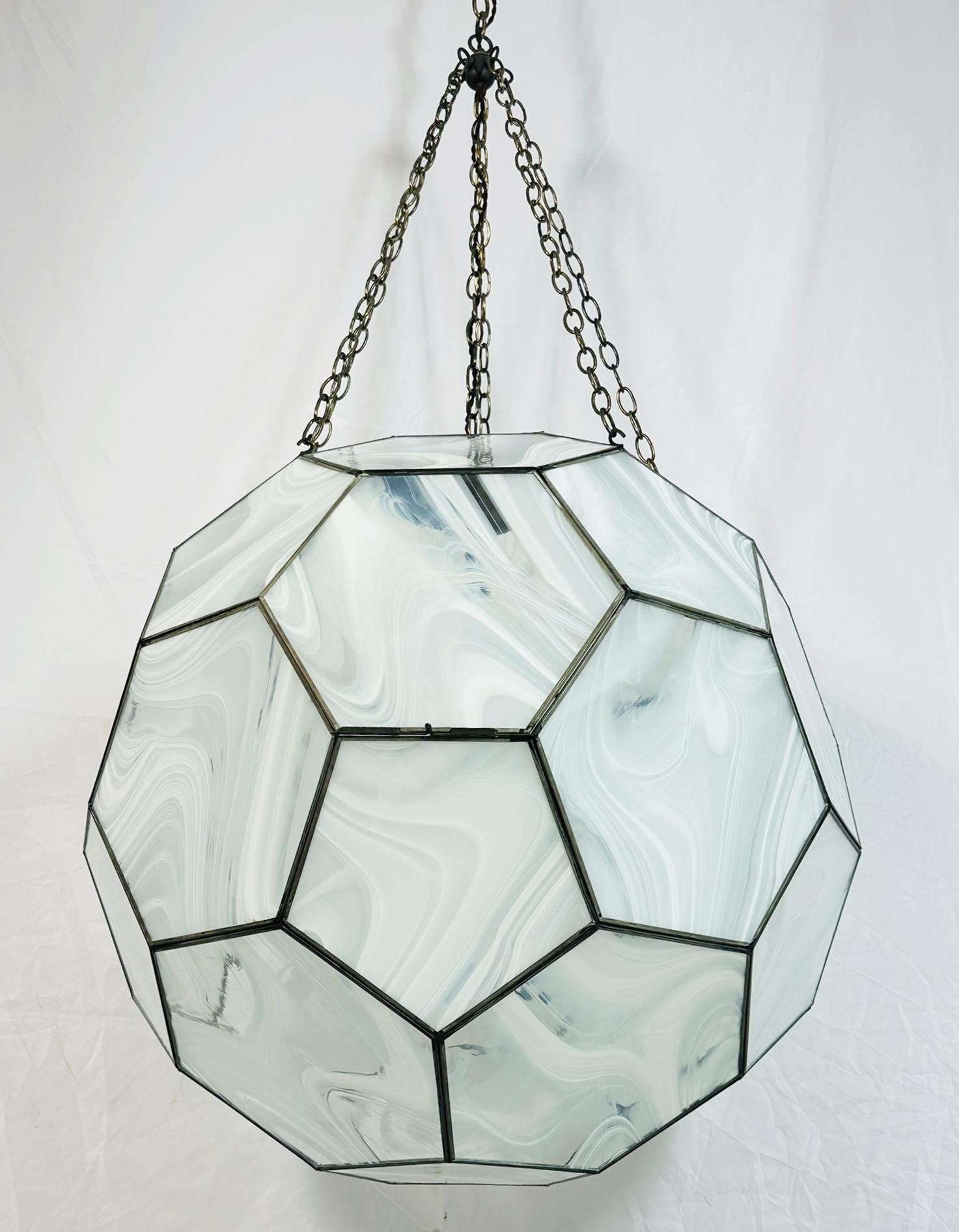 Llamativa lámpara de araña en forma de panal de Clate Grunden, un maestro del diseño de iluminación a medida, conocido por sus atrevidas formas geométricas y su artesanía. Esta impresionante pieza presenta una estructura de cúpula geodésica