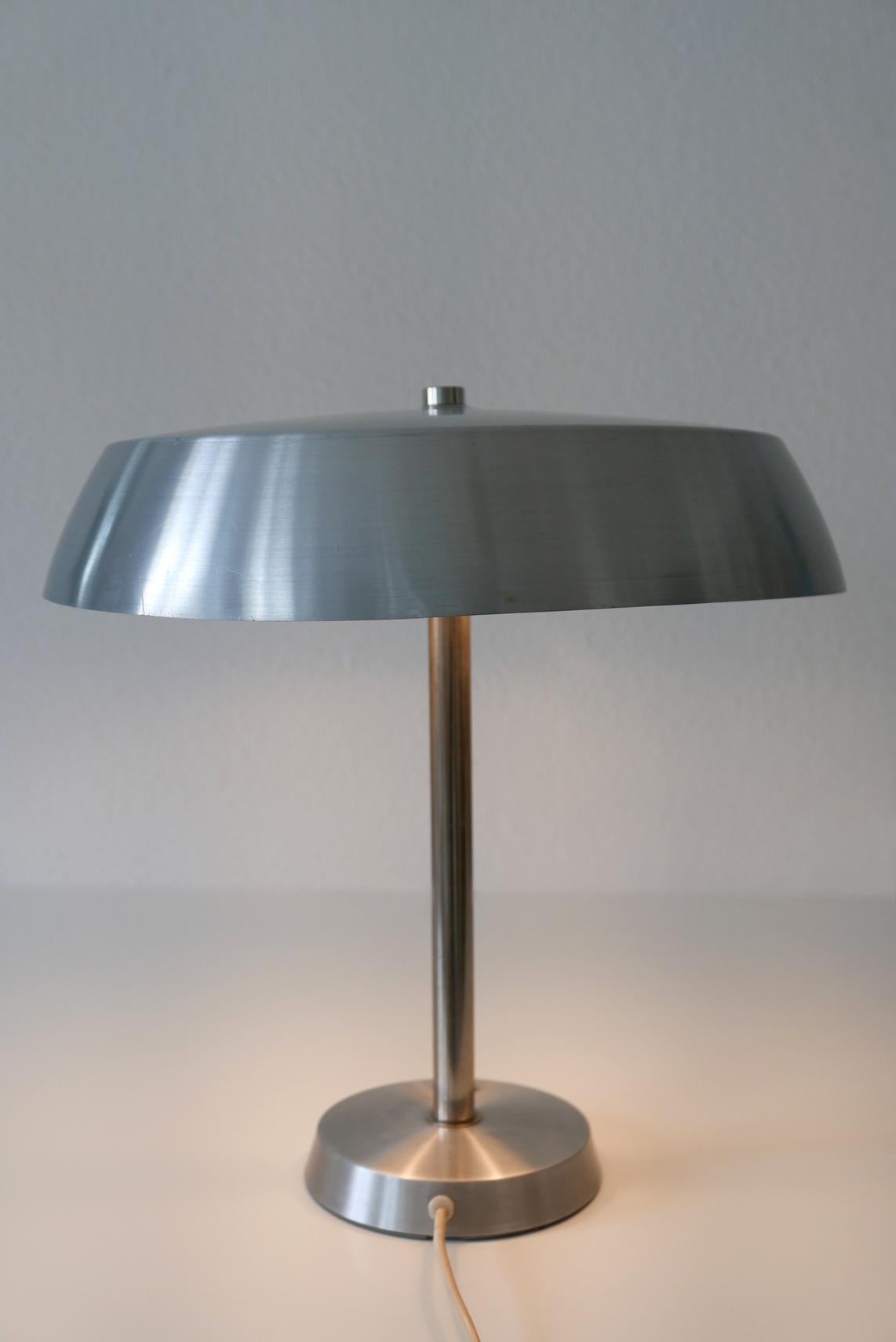 Elegant Mid-Century Modern table lamp by SIS, 1960s, Germany.

Executed in polished aluminium sheet and nickel-plated steel tube. The lamp needs 2 x E27 Edison screw fit bulbs, is wired, and in working condition. It runs both on 110 / 230