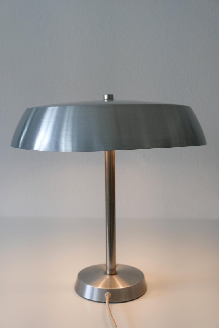 Elegant Mid-Century Modern table lamp by SIS, 1960s, Germany.

Executed in polished aluminium sheet and nickel-plated steel tube. The lamp needs 2 x E27 Edison screw fit bulbs, is wired, and in working condition. It runs both on 110 / 230