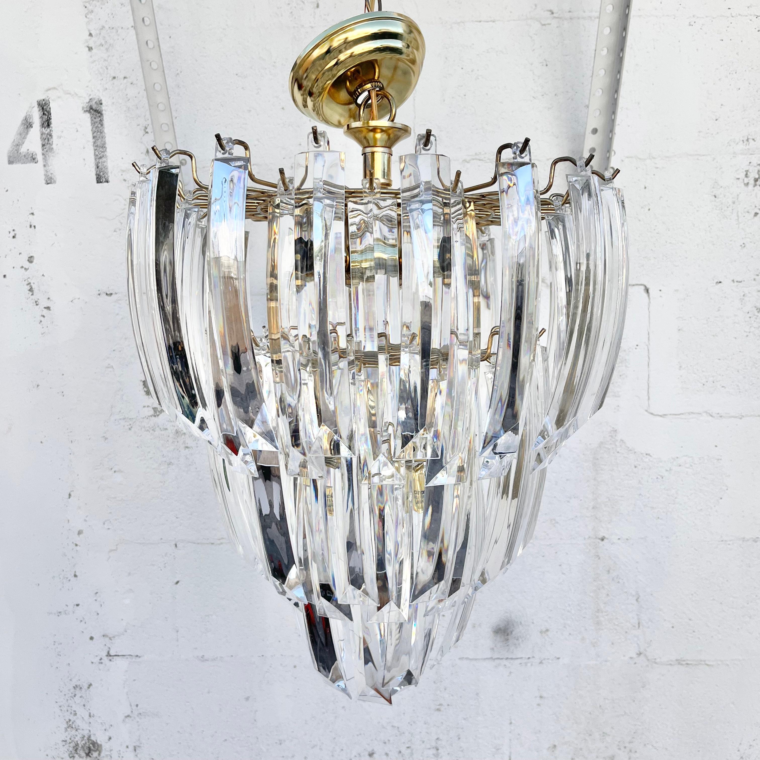 Large Mid-Century Modern three-tier Prism Lucite chandelier. Circa 1970s 
This medium to large scale chandelier features a brass plated metal frame with three tiers of about 8 inches long and slightly arched lucite crystals, with 10 chandelier