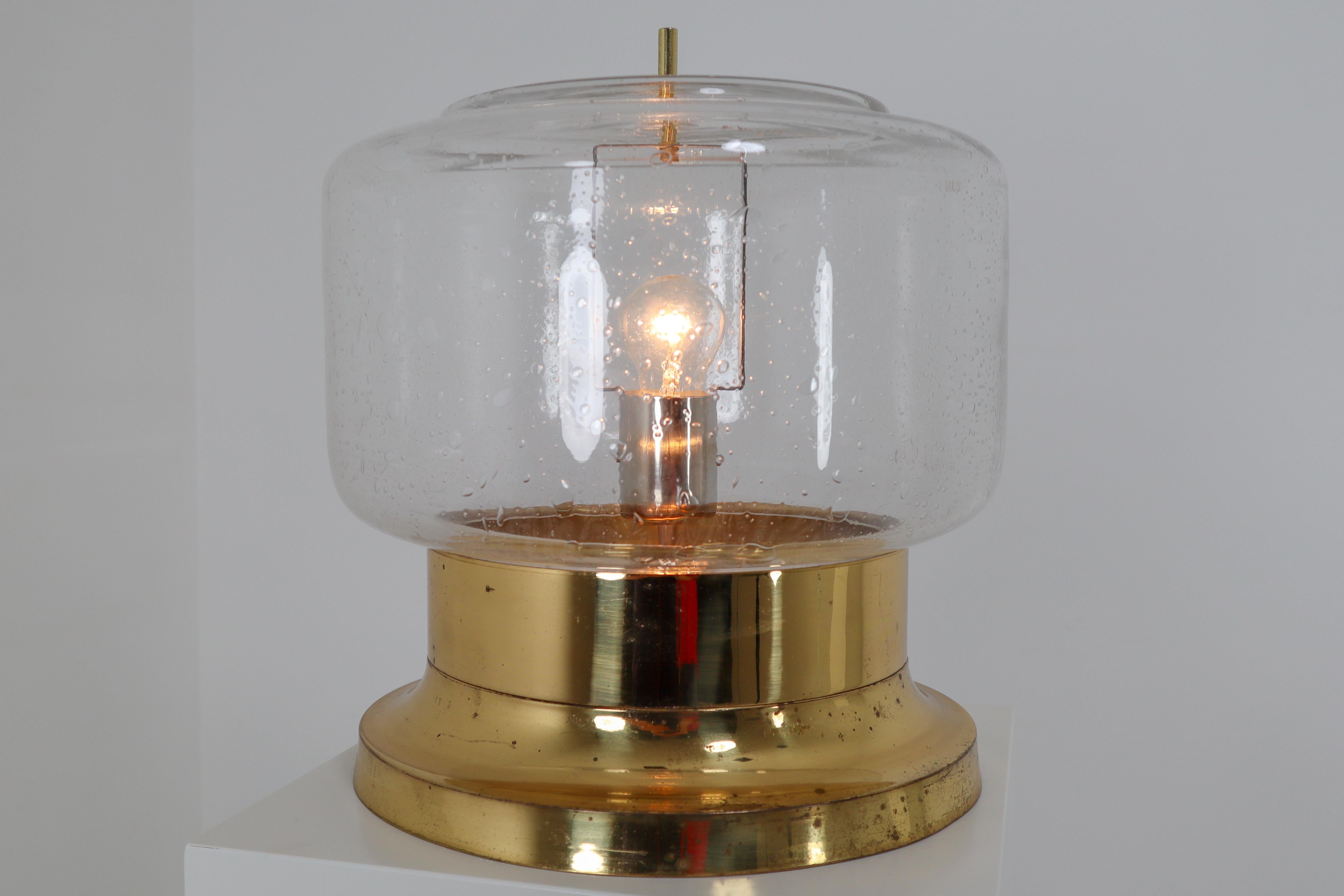 Large European midcentury table lamp, Austria, 1960s. The handblown clear glass contains air bubbles of varying sizes and density that create a wonderful light effect. The base is made of solid brass. These table lamp will contribute to a luxurious