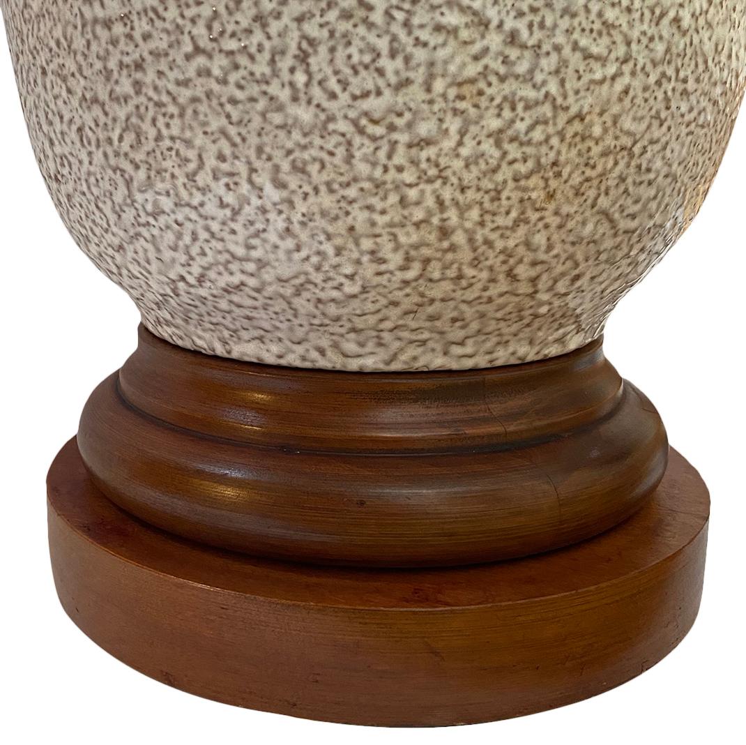 A large circa 1960's single Italian textured and glazed porcelain lamp with wooden base.

Measurements:
Height of body: 23