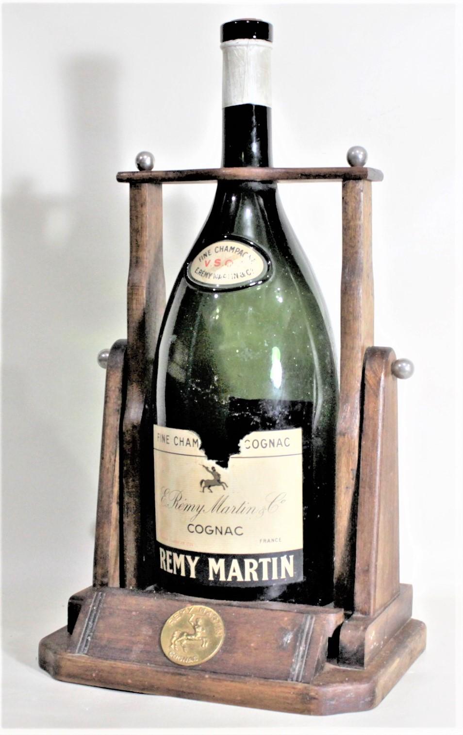 This large Mid-Century Modern era wooden bottle tipper was likely made and bottled in the United States for the premier French cognac Remy Martin in circa 1965. The bottle tipper is made of stained softwood with chrome lug nuts that secure the top