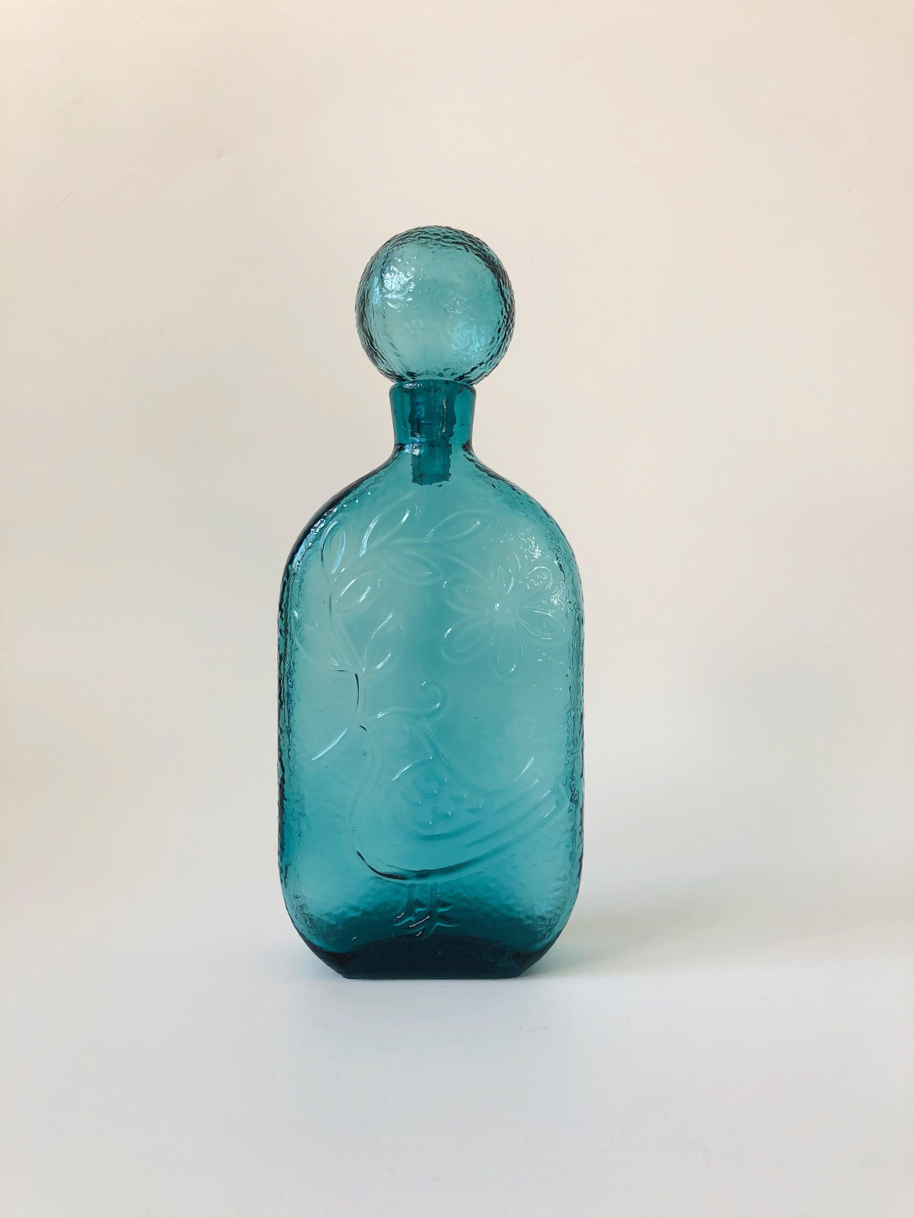 A wonderful large mid century glass decanter designed by Wayne Husted for Stelvia Glass of Italy. Beautiful textured design of a bird holding a flower vine on one side. Topped off by an oversized spherical stopper.
     