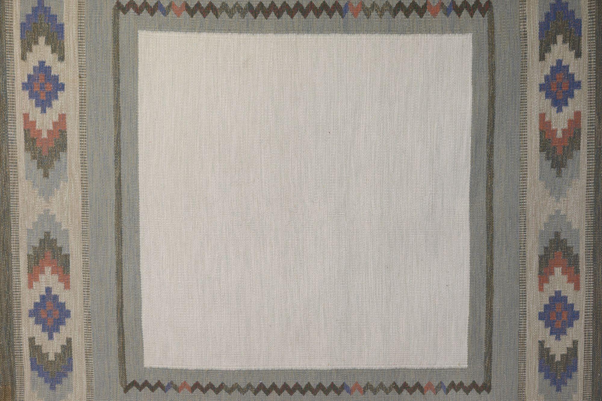 Kilim sueco de mediados de siglo, de gran tamaño, con bordes geométricos y un gran campo central claro. En tonos verdes, azules y crema. Suecia hacia 1960. Todas nuestras alfombras se someten a un proceso de limpieza profesional. Sin embargo, debido