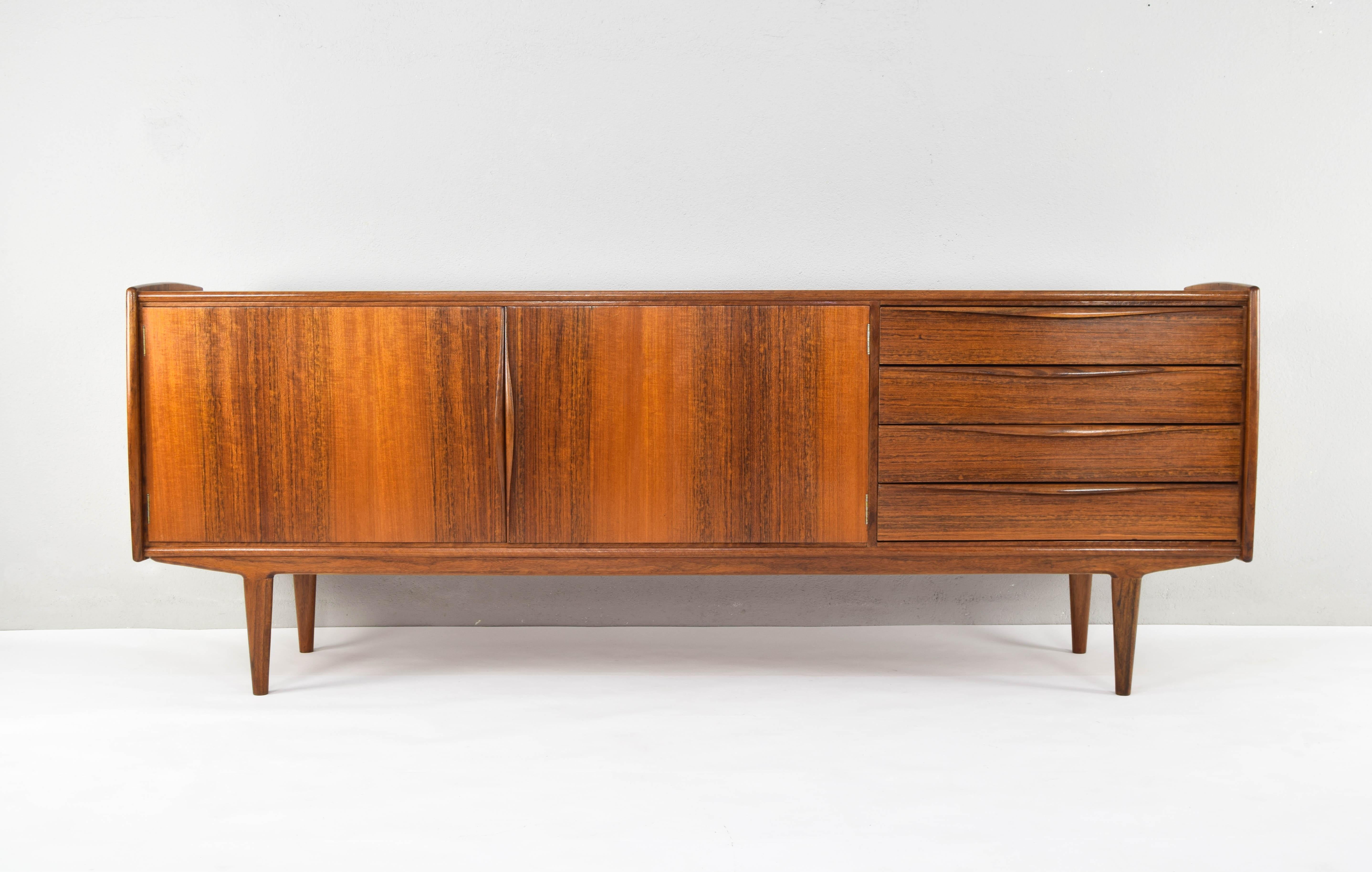 Large sideboard from the 60s with beautiful teak veneer. On the right it has two compartment doors with shelves and on the right with four drawers, the first one with compartments for cutlery.
Sideboard with beautiful curved lines and