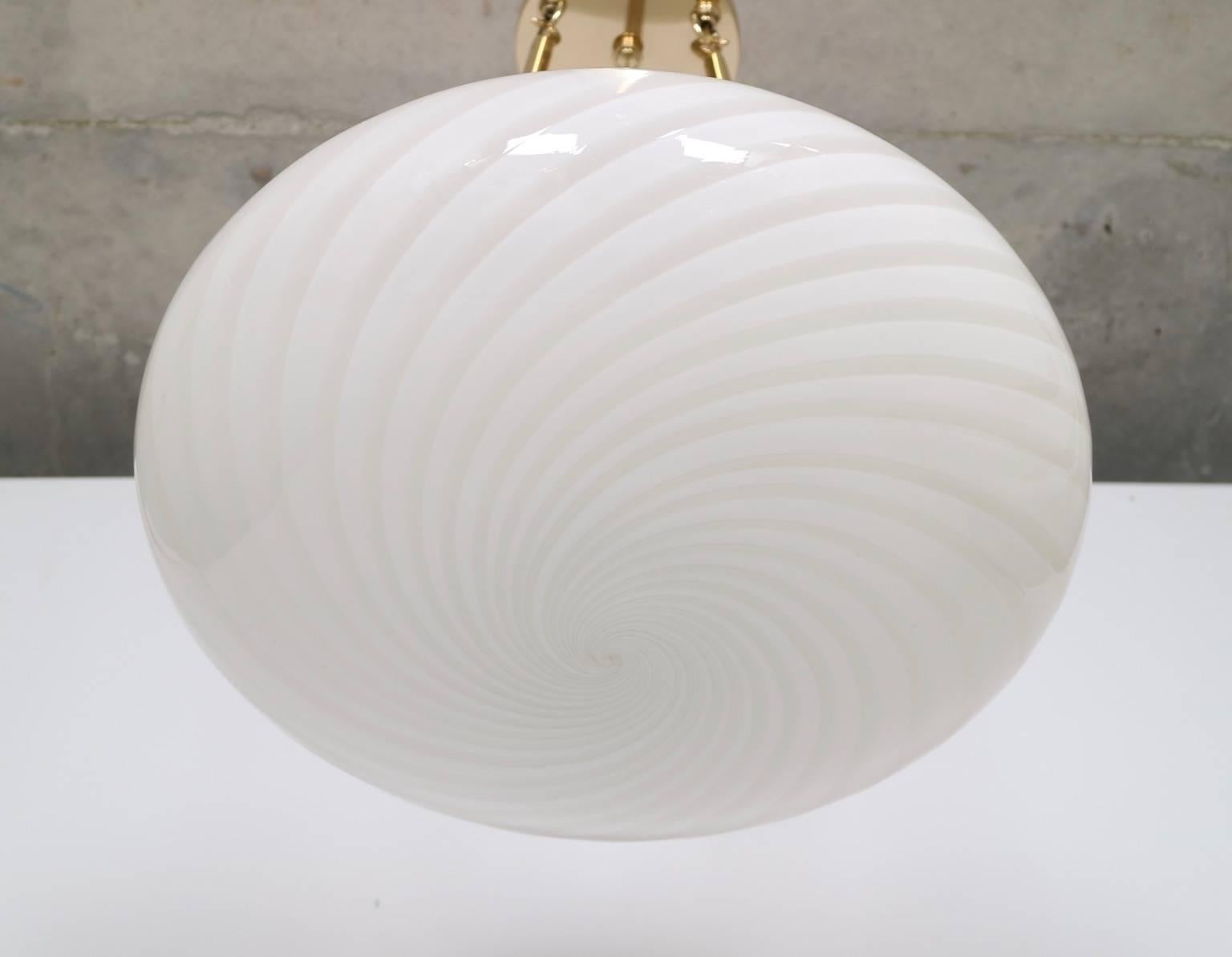 Large midcentury Murano glass pendant by Venini with signature swirl glass technique. The pendant hangs by three brass arms and takes three regular light bulbs. This pendant has been fully restored with new sockets and wiring. 

This piece is in