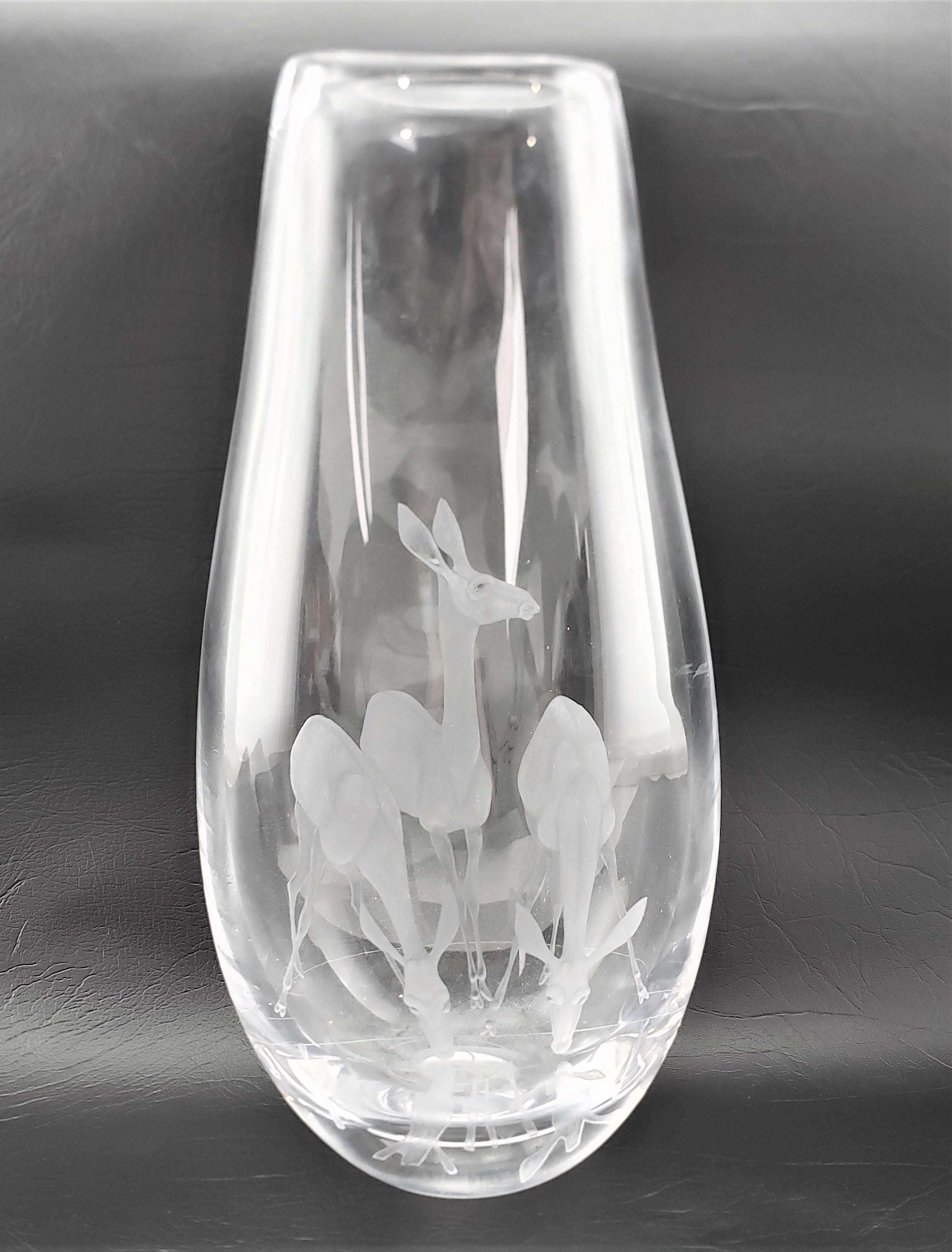 This large clear art glass vase is signed with the Kosta Boda maker's signature and this pattern is attributed to Vicke Lindstrand and dates to approximately 1965 and done in the period Mid-Century Modern style. The vase is done in a thick clear