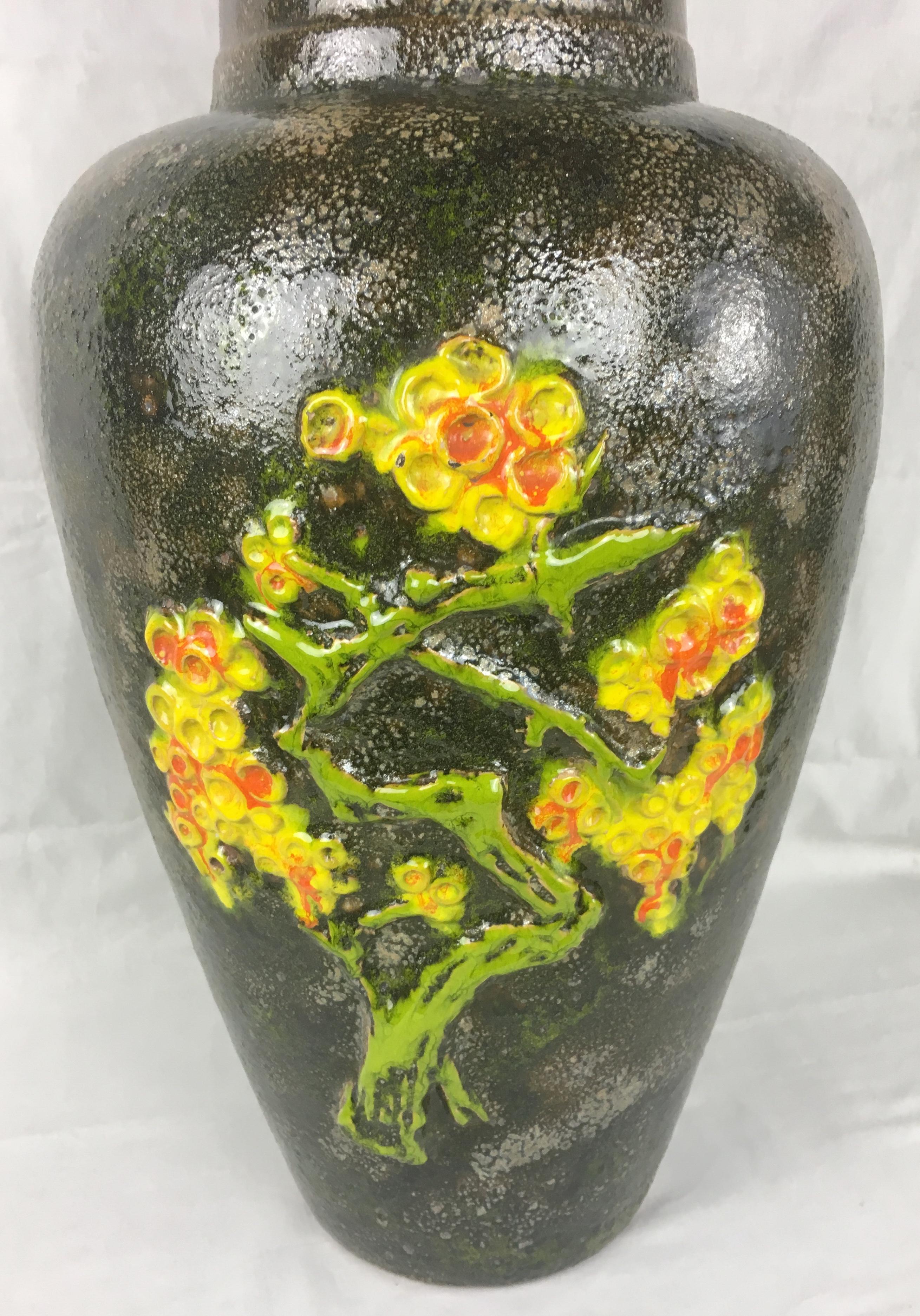 This tall collectable mid- 20th Century West Germany ceramic floor vase was produced circa 1965 by the renowned producer of studio pottery, Scheurich Keramik. The vase features lovely black and grey hues with classical 1960s green, orange and yellow