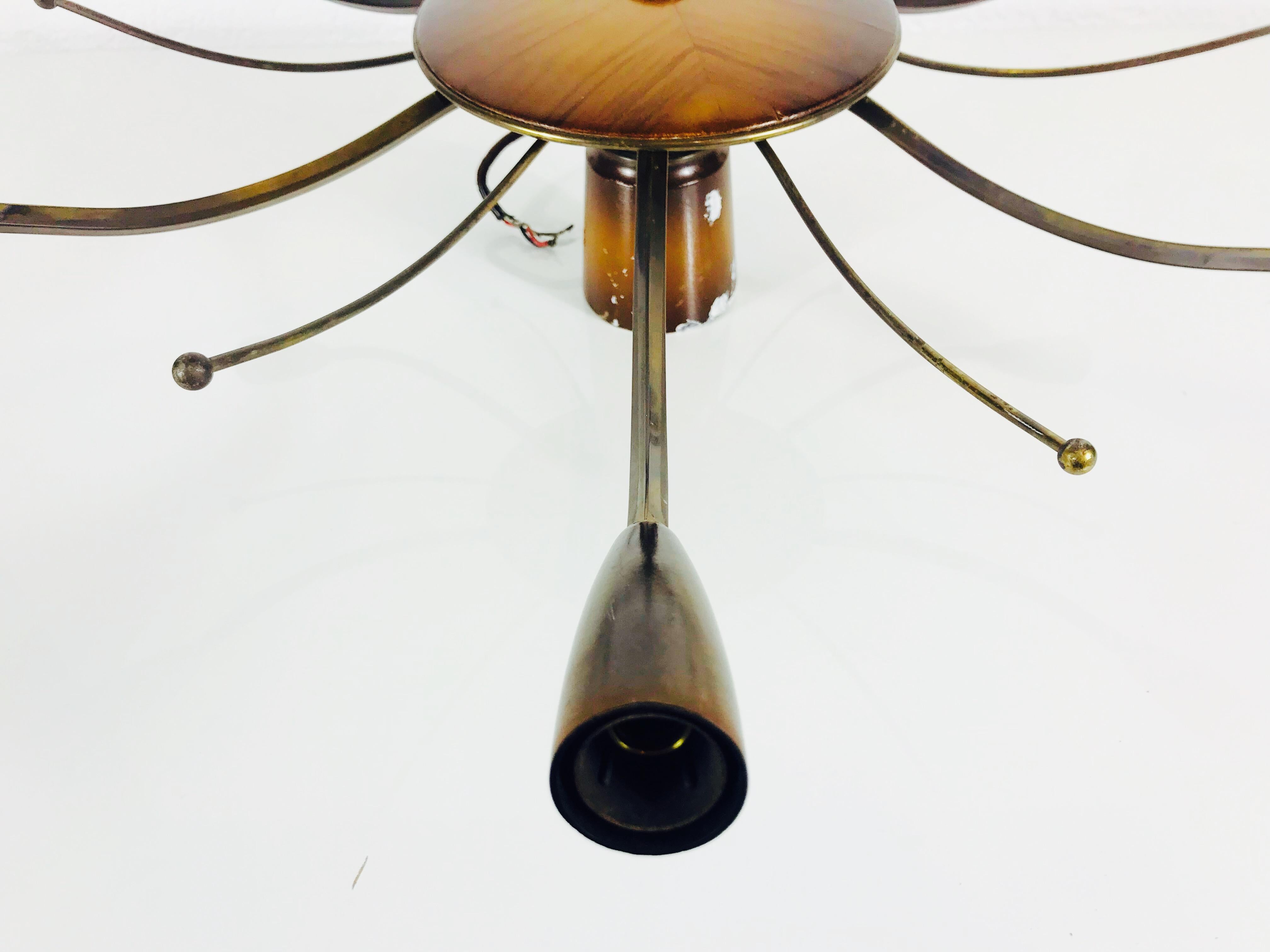 A sputnik chandelier made in Germany in the 1950s. It is fascinating with its six brass arms, each of it with an E14 light bulb. Plus six other brass arms without light bulbs. The design and shape of the lamp is similar to a spider. The body of the