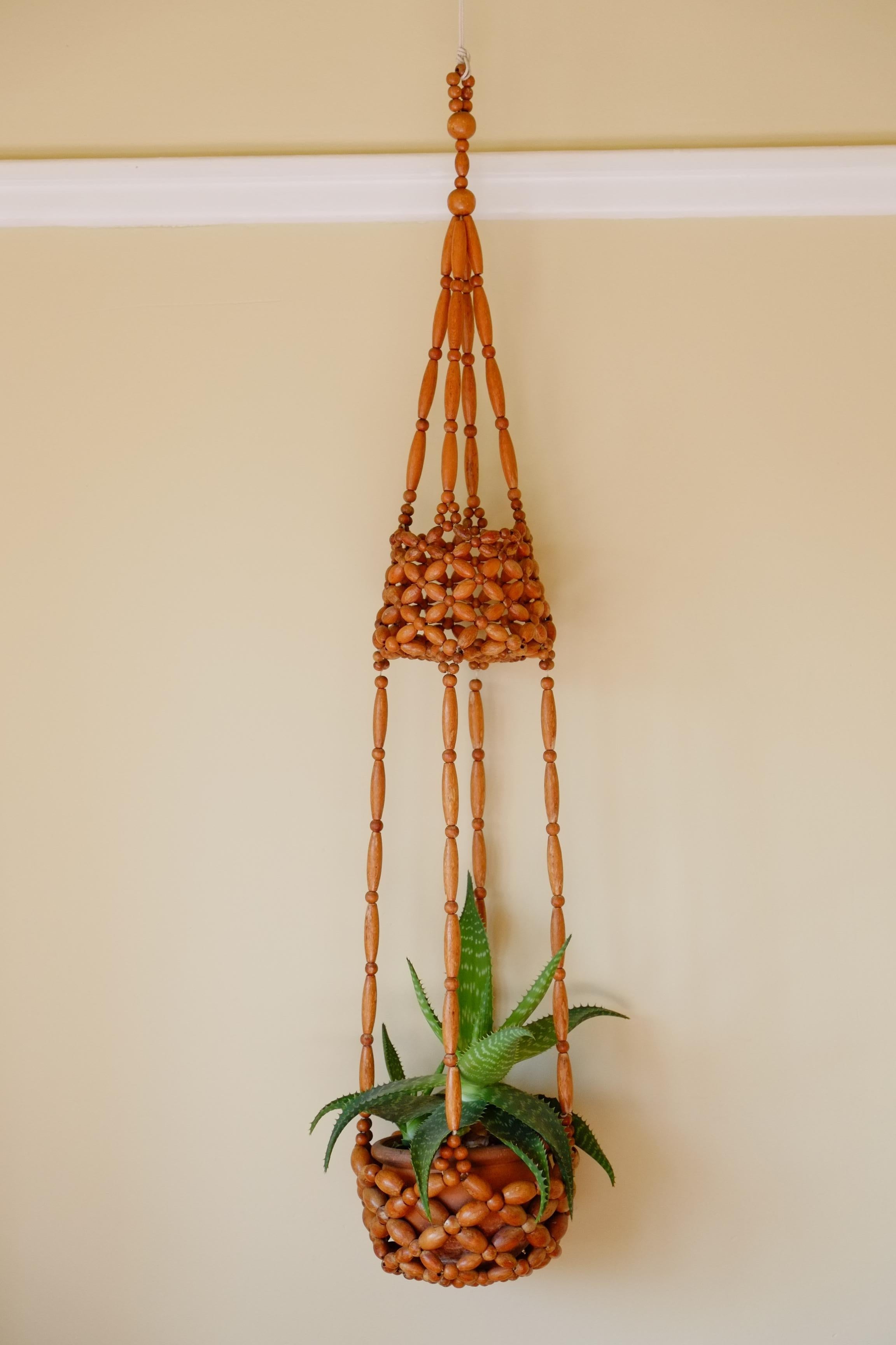 The most beautiful midcentury beaded hanging planter. 

This planter is is great condition and is rare to find intact. Beautiful honey coloured wood beads, strung into a simple flower pattern. Two hanging bowl sections with tapering sides.
