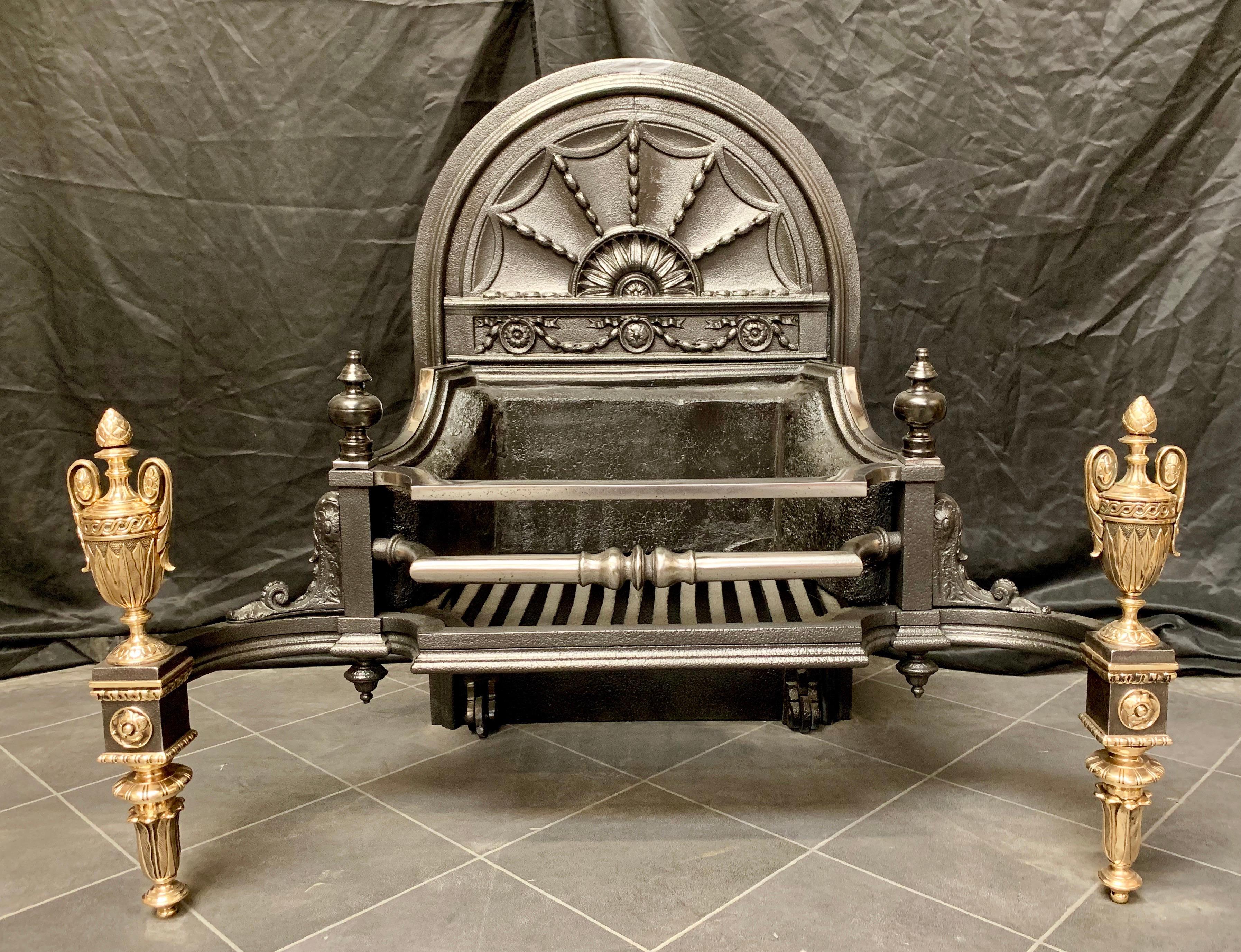 A large and elegant cast iron and bronze Victorian fire grate with a high arched sunburst fire back in the Georgian manner. The two barred polished grate is flanked by a pair of decorative cast shoulders capped by a pair of bobbin finials. The whole