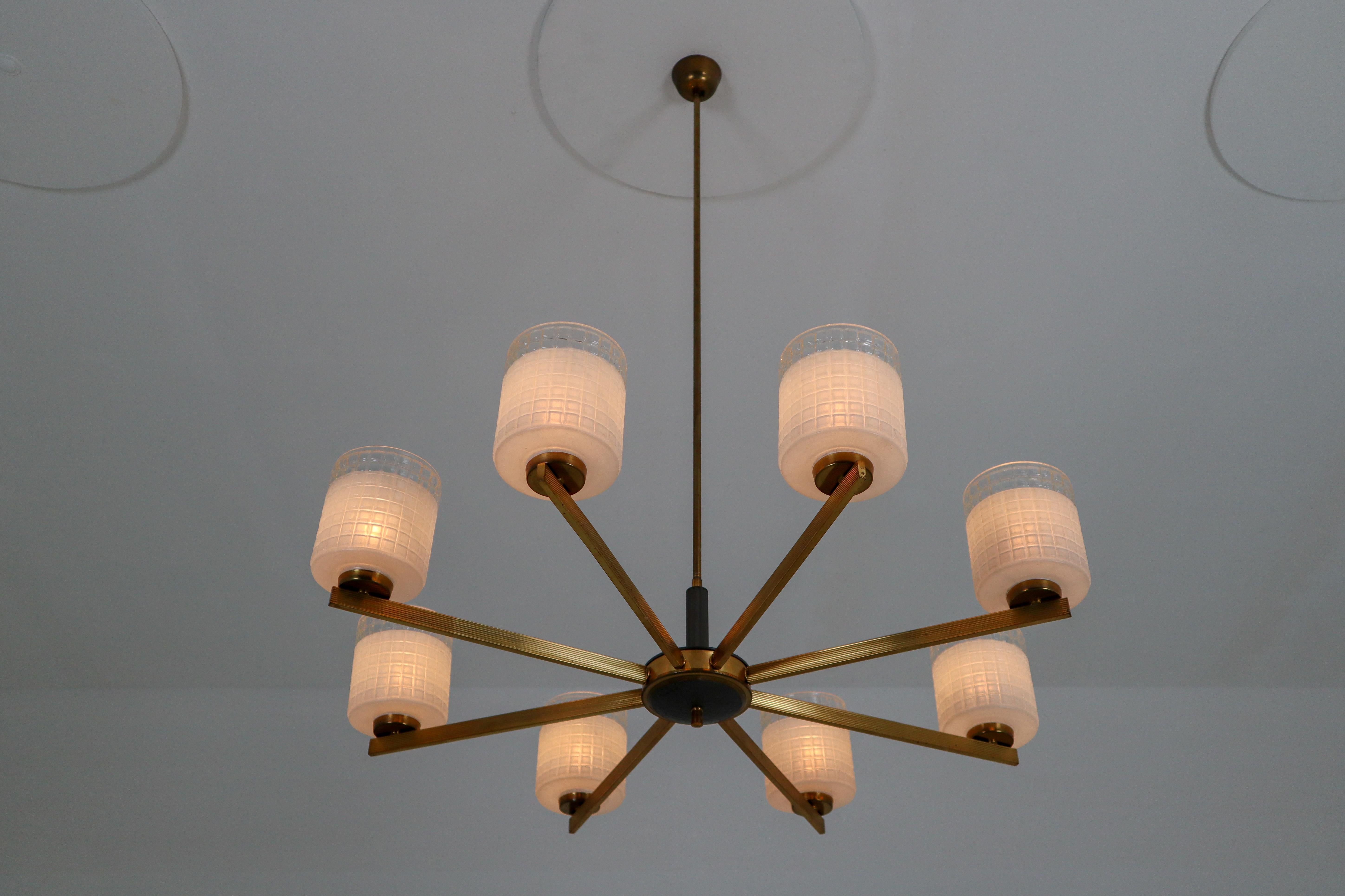 Large Danish modern style chandelier, 1950s, featuring eight rectangular profiled brass spokes, structured glass shades. The patinated brass fixture beautifully combines with the structured glass. Due their materials and size, these lights will