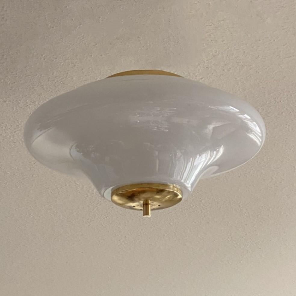 A large Bauhaus UFO opaline glass and brass two-light flush mount manufactured in Germany circa 1940-1949. This flush mount can also be used as a pendant by adding a chain. In very good original condition, no damages, rewired. It takes two Edison