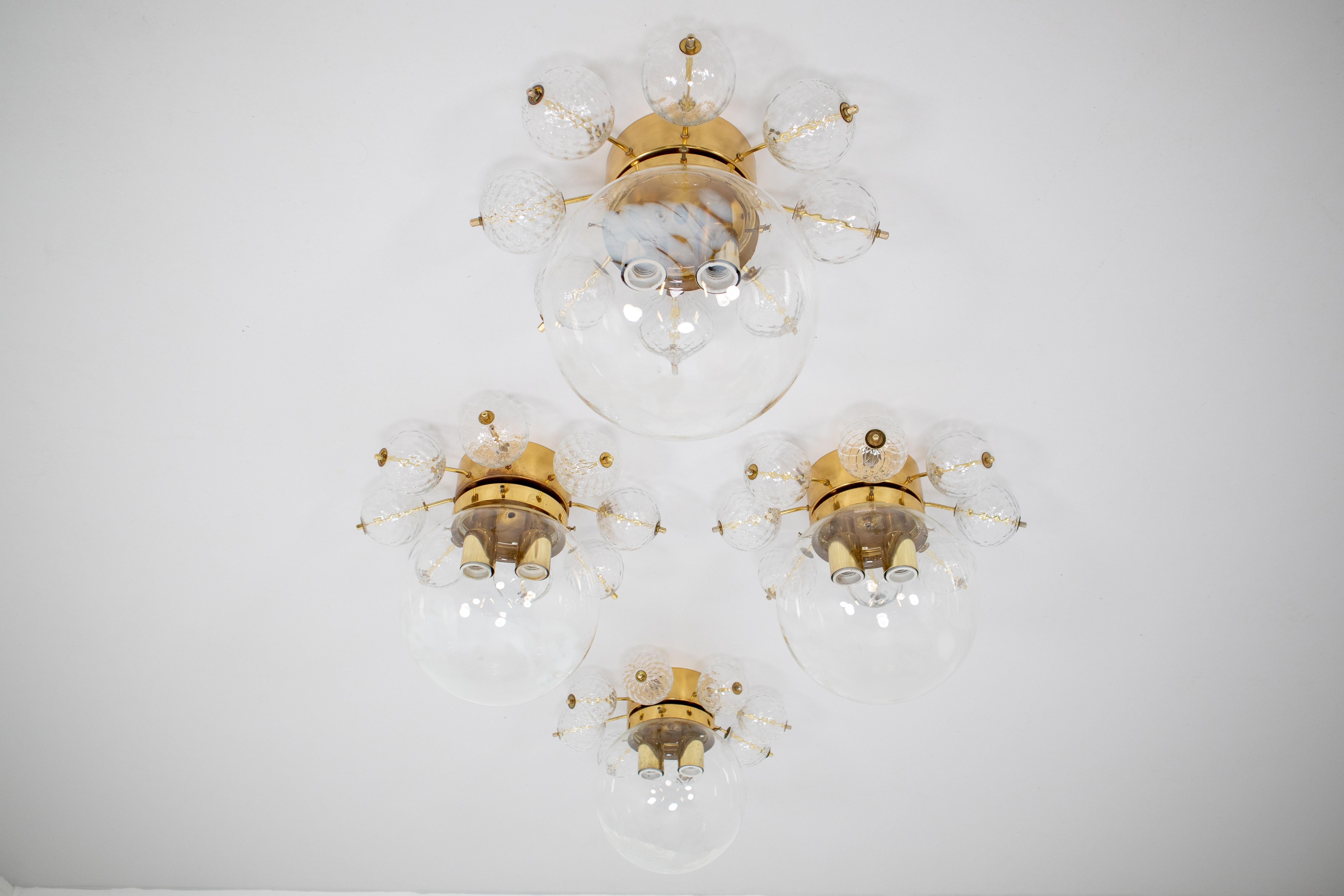 Large ceiling lamp-chandeliers with brass base and large handblown art-glass globe. These clear handblown glass globe are decorated with white streaks. The globe show a different and unique semi transparent, diffuse surface, which looks wonderful.