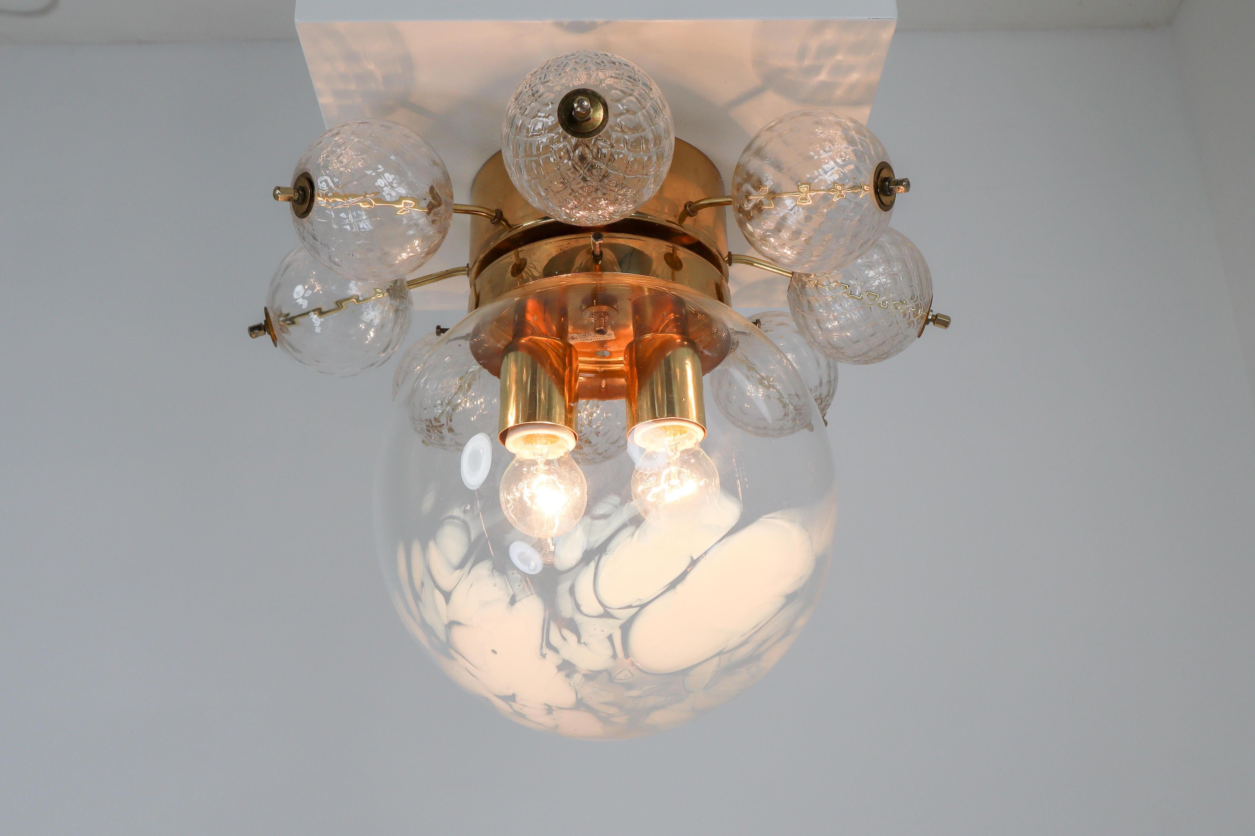 Large ceiling lamp-chandeliers with brass base and large hand blown art-glass globe. These clear hand blown glass globe are decorated with white streaks. The globe show a different and unique semi transparent, diffuse surface, which looks wonderful.